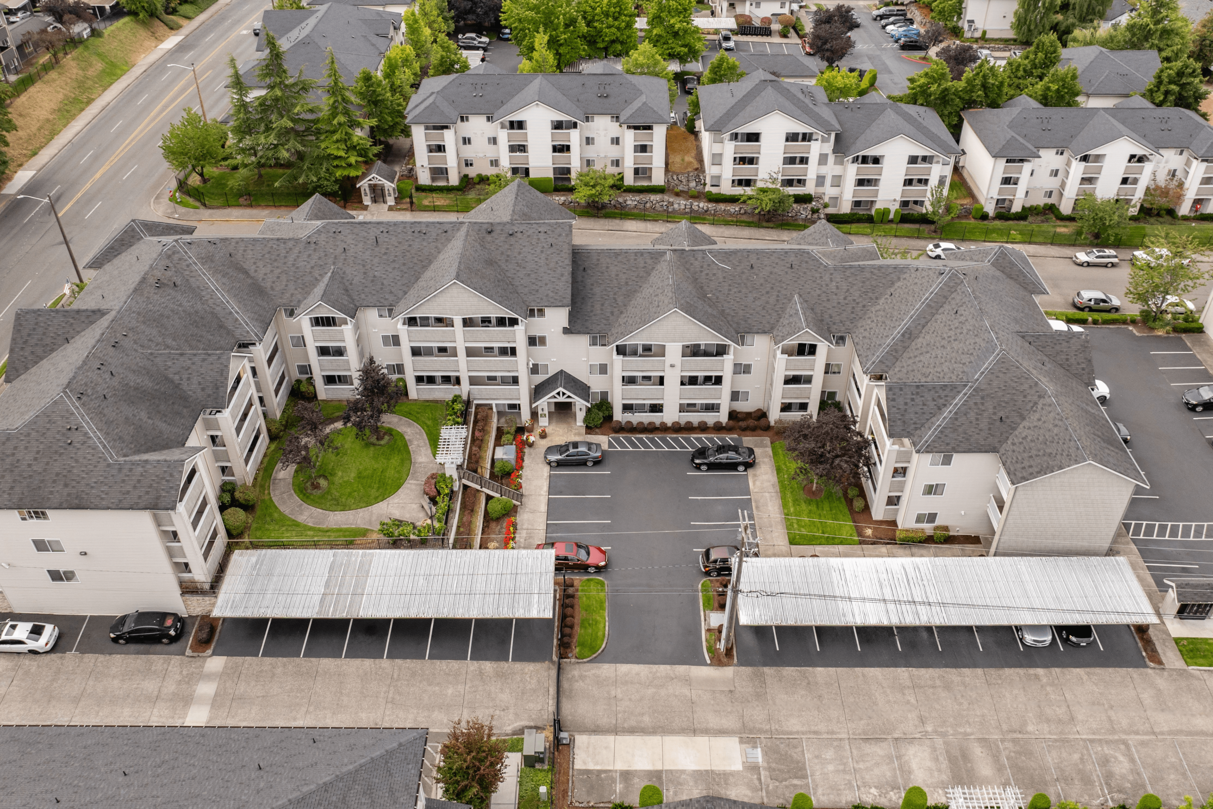 Charming aerial view of a modern apartment complex with manicured gardens, ample parking, and inviting pathways.