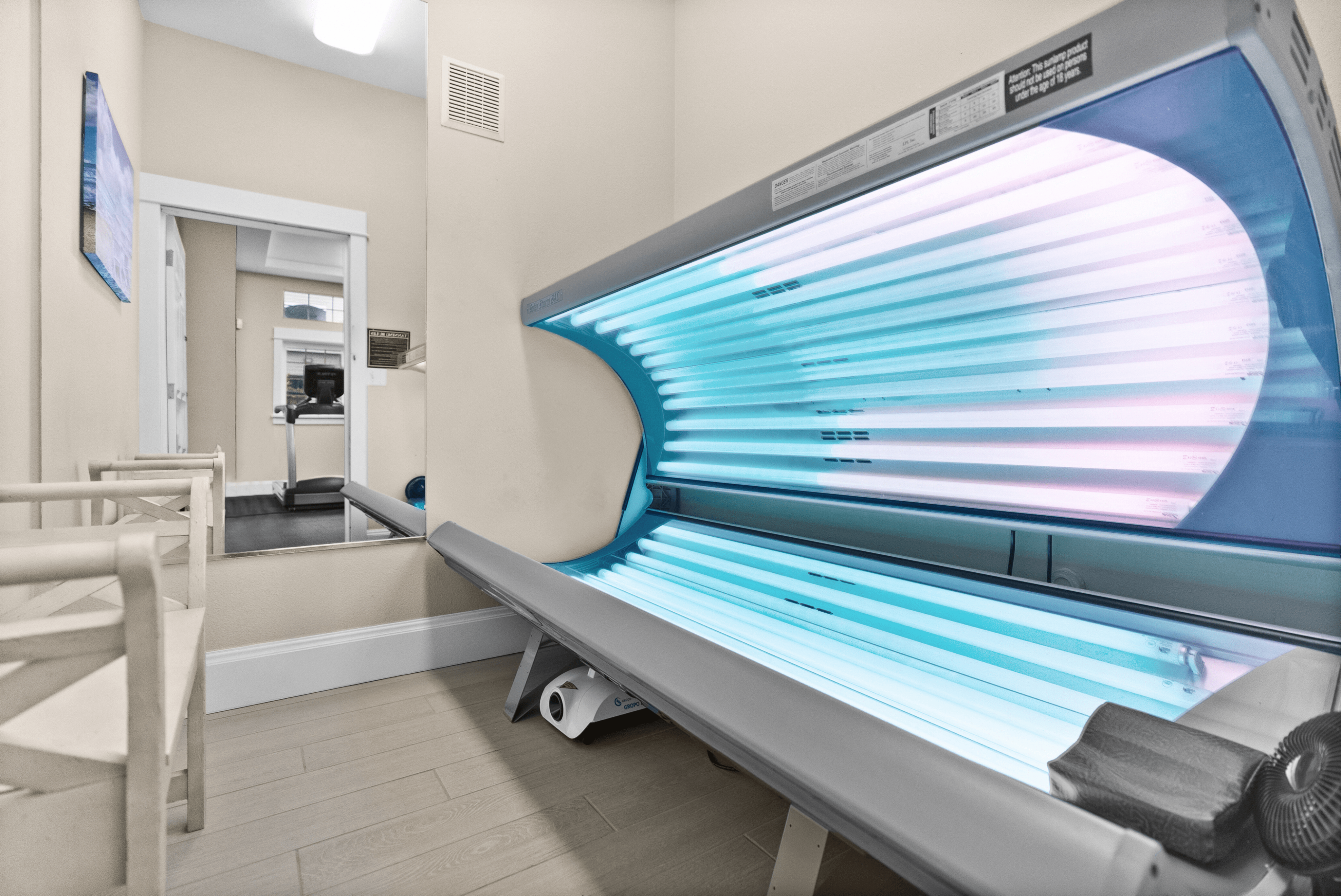 Luxurious indoor tanning room featuring a modern sunbed and adjacent fitness area, promising a vibrant and healthy lifestyle.