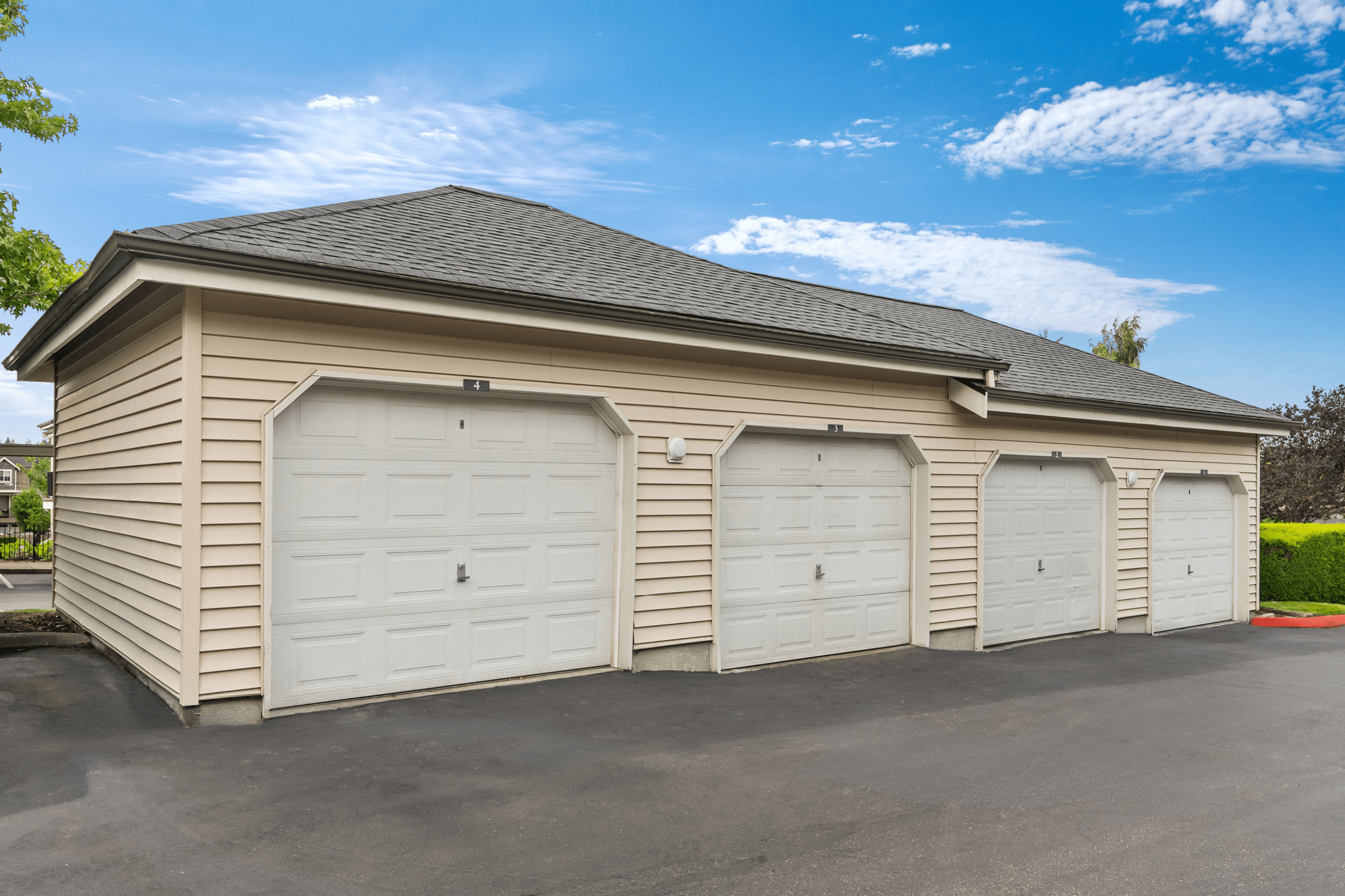 Impressive apartment complex showcasing four secure garage spaces with pristine white doors under a clear blue sky.
