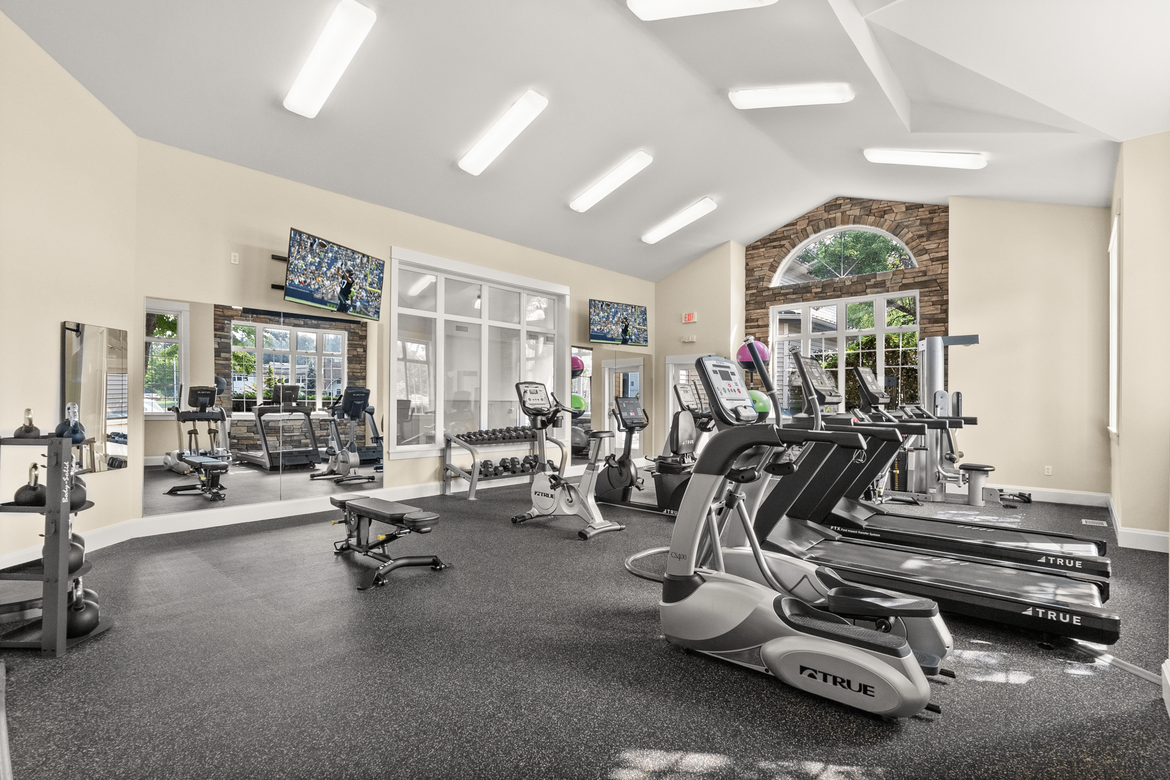 Bright, modern fitness center featuring state-of-the-art exercise equipment, large windows, and sleek design.