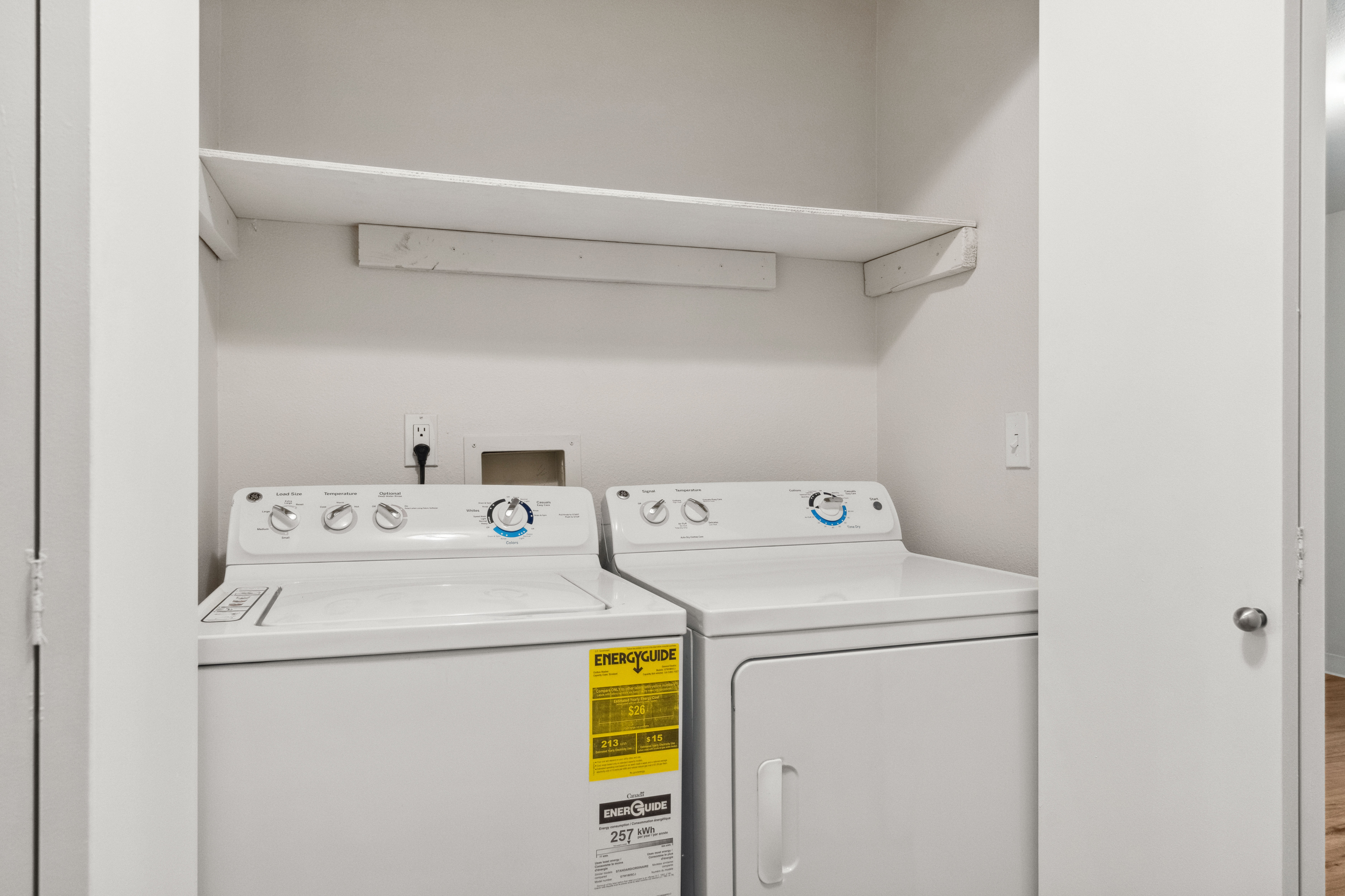 Bright and efficient laundry area featuring modern washer and dryer with convenient shelving.