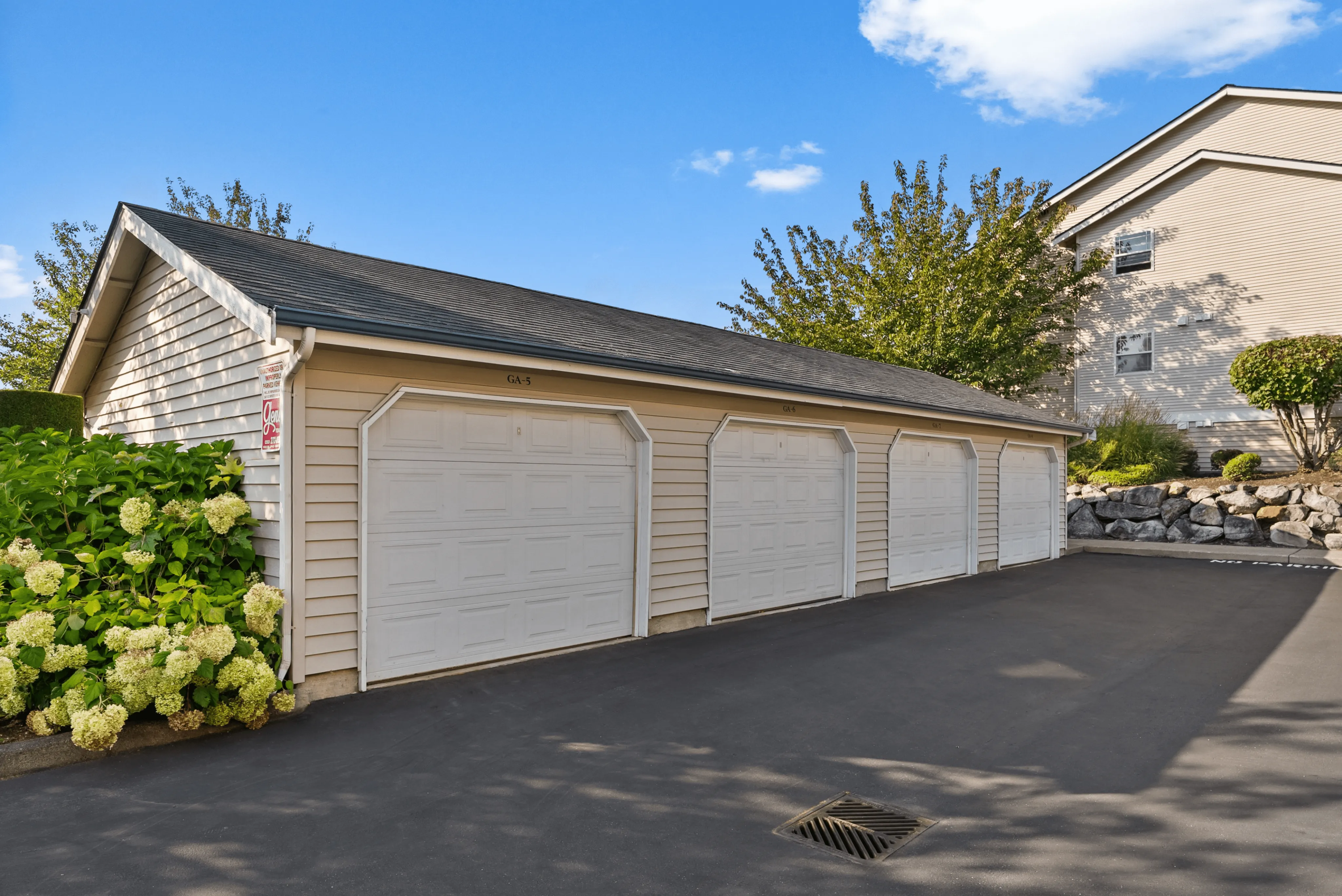 Charming residential setting featuring a clean, well-maintained garage surrounded by lush greenery and modern landscaping.