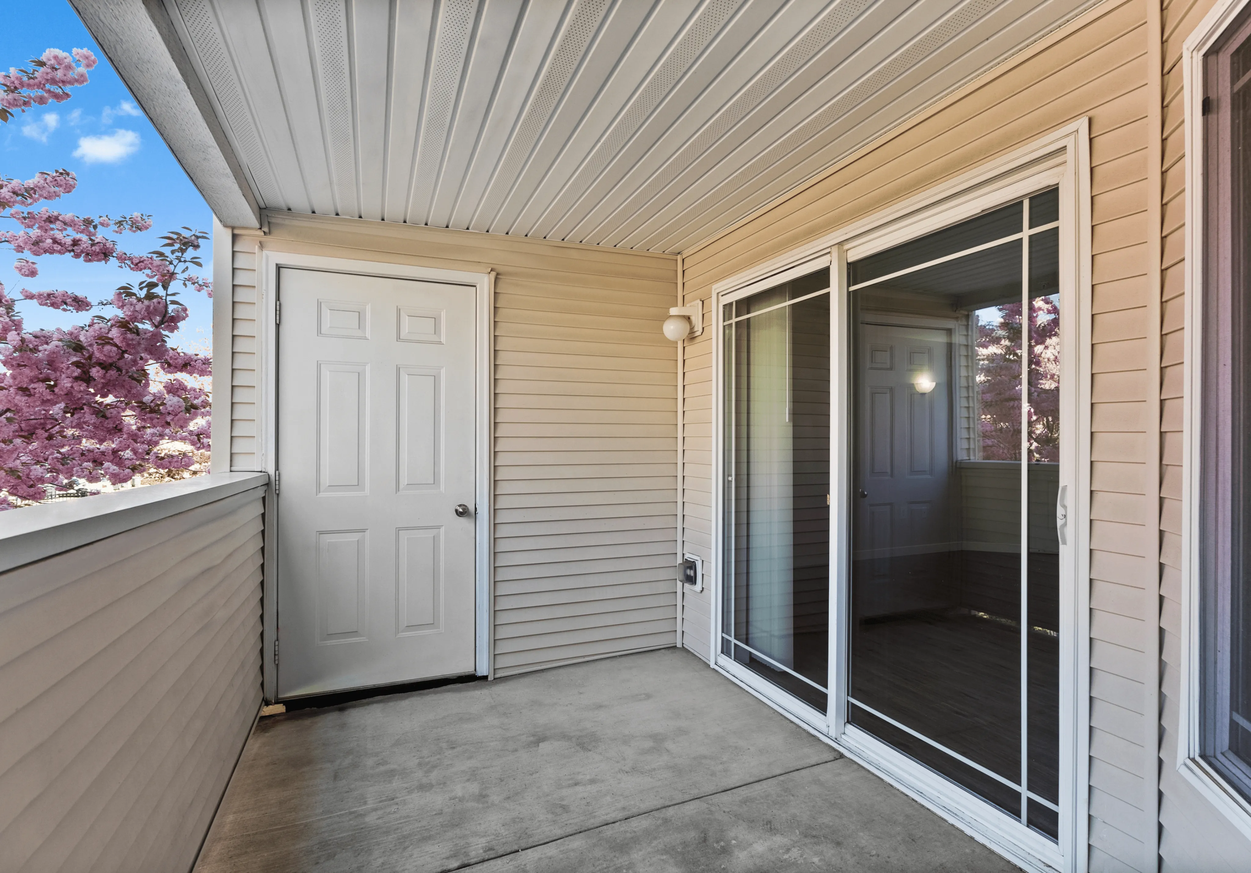 Inviting balcony space with sliding glass doors, perfect for enjoying vibrant views of blooming cherry blossoms.