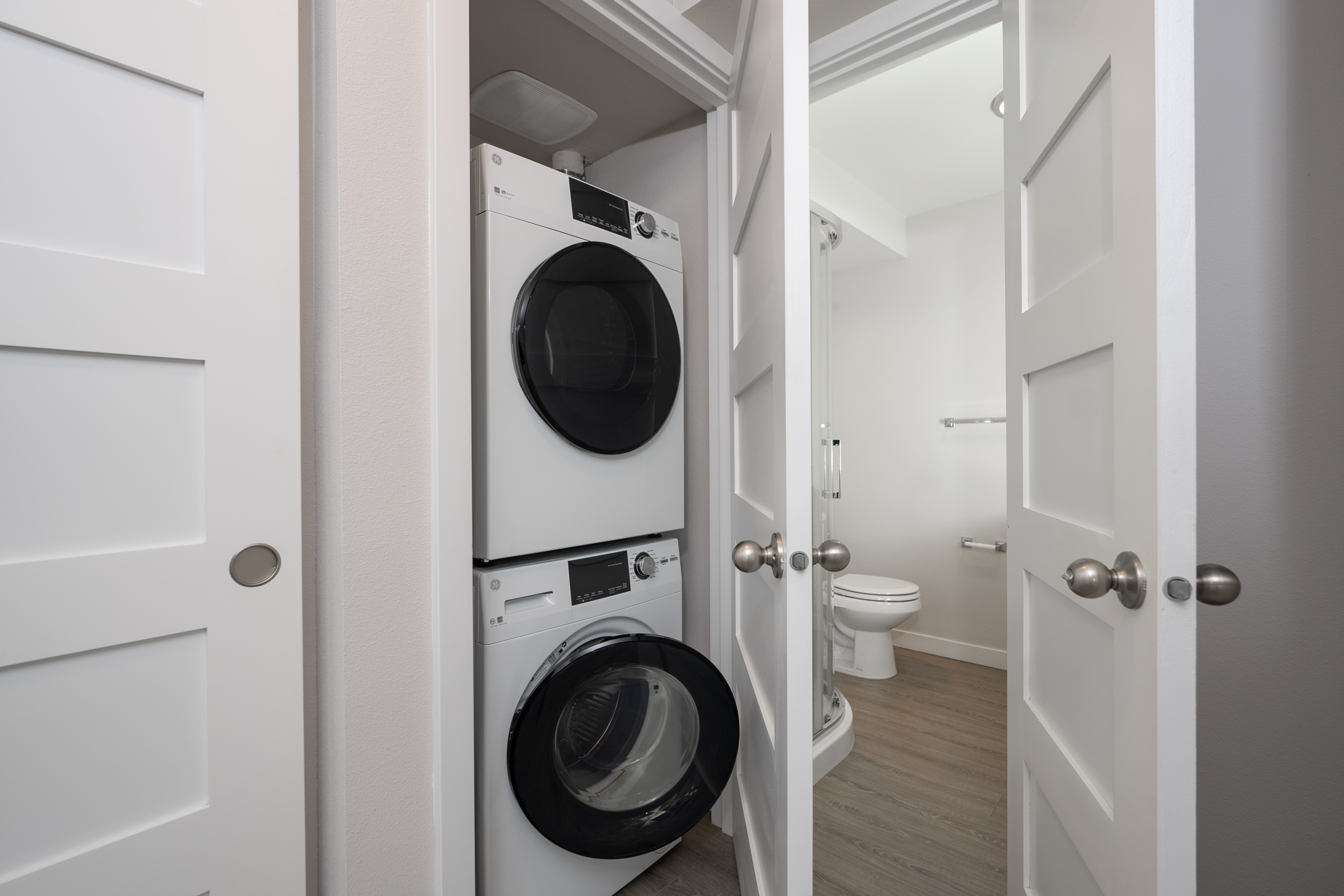 Modern apartment laundry setup with a sleek stackable washer and dryer conveniently housed in a closet near a stylish bathroom.