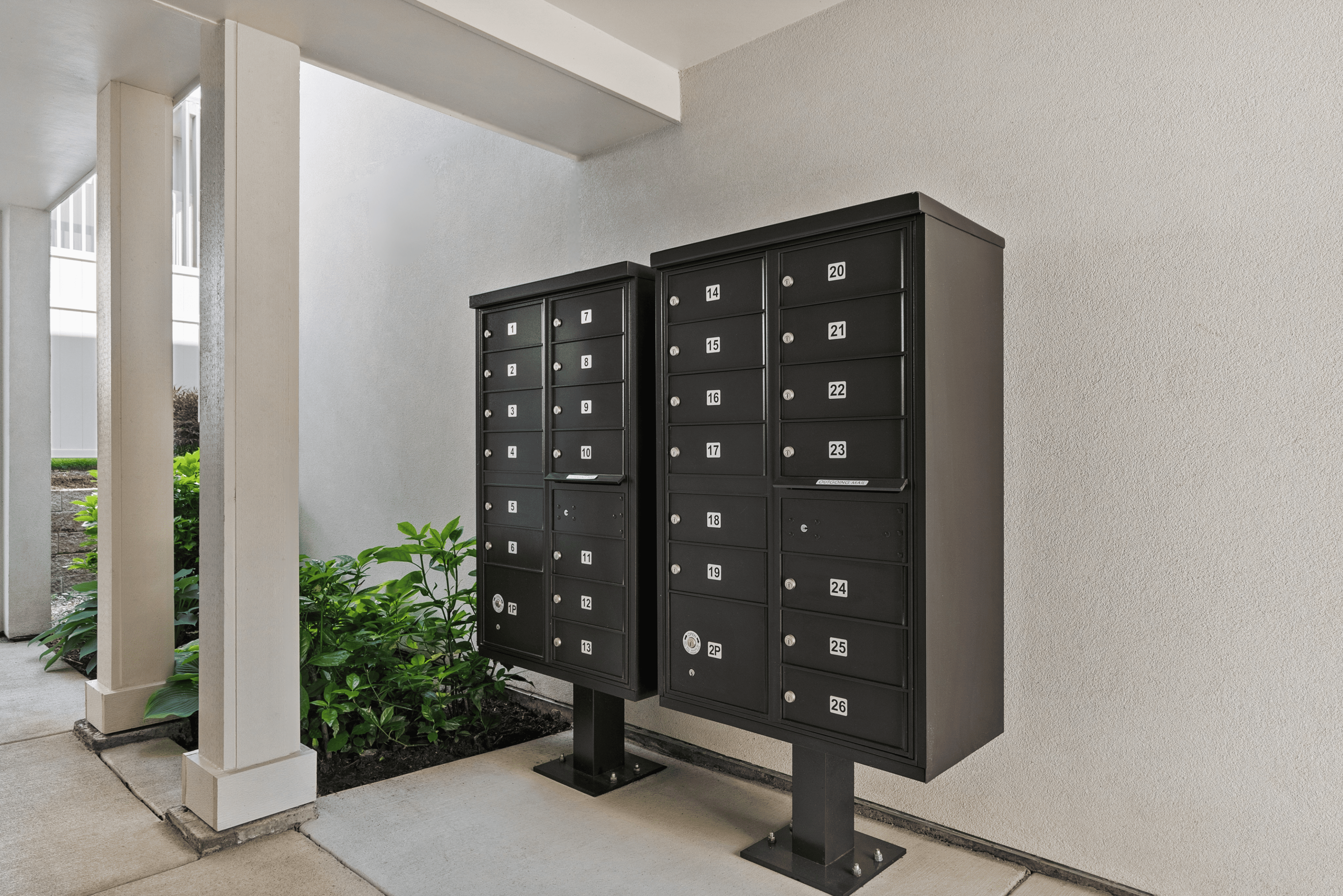 Modern mailboxes in a sleek, inviting apartment entrance, surrounded by lush greenery.