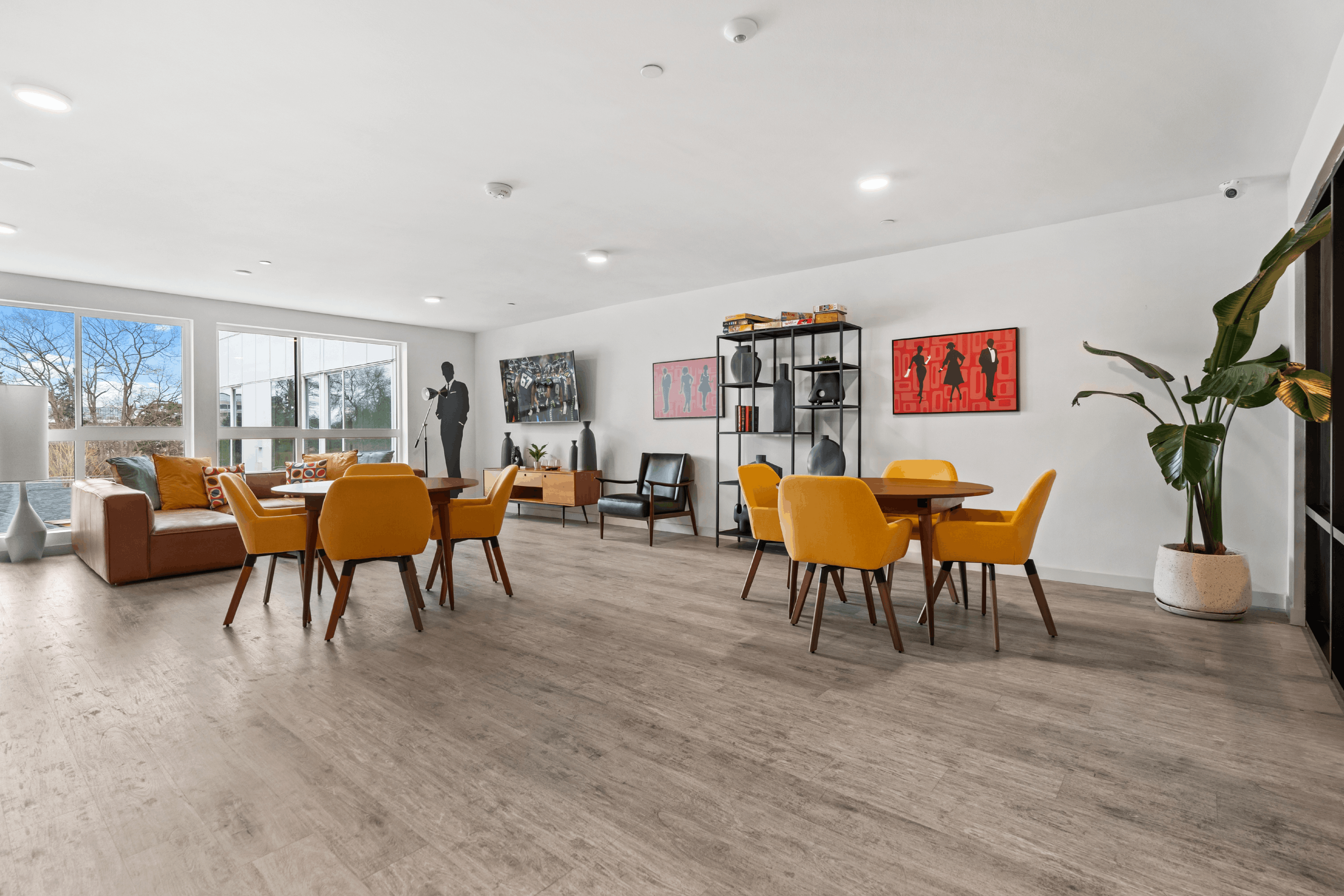 Contemporary lounge area featuring vibrant mustard chairs, a cozy sofa, and chic wall art, illuminated by natural light from large windows.