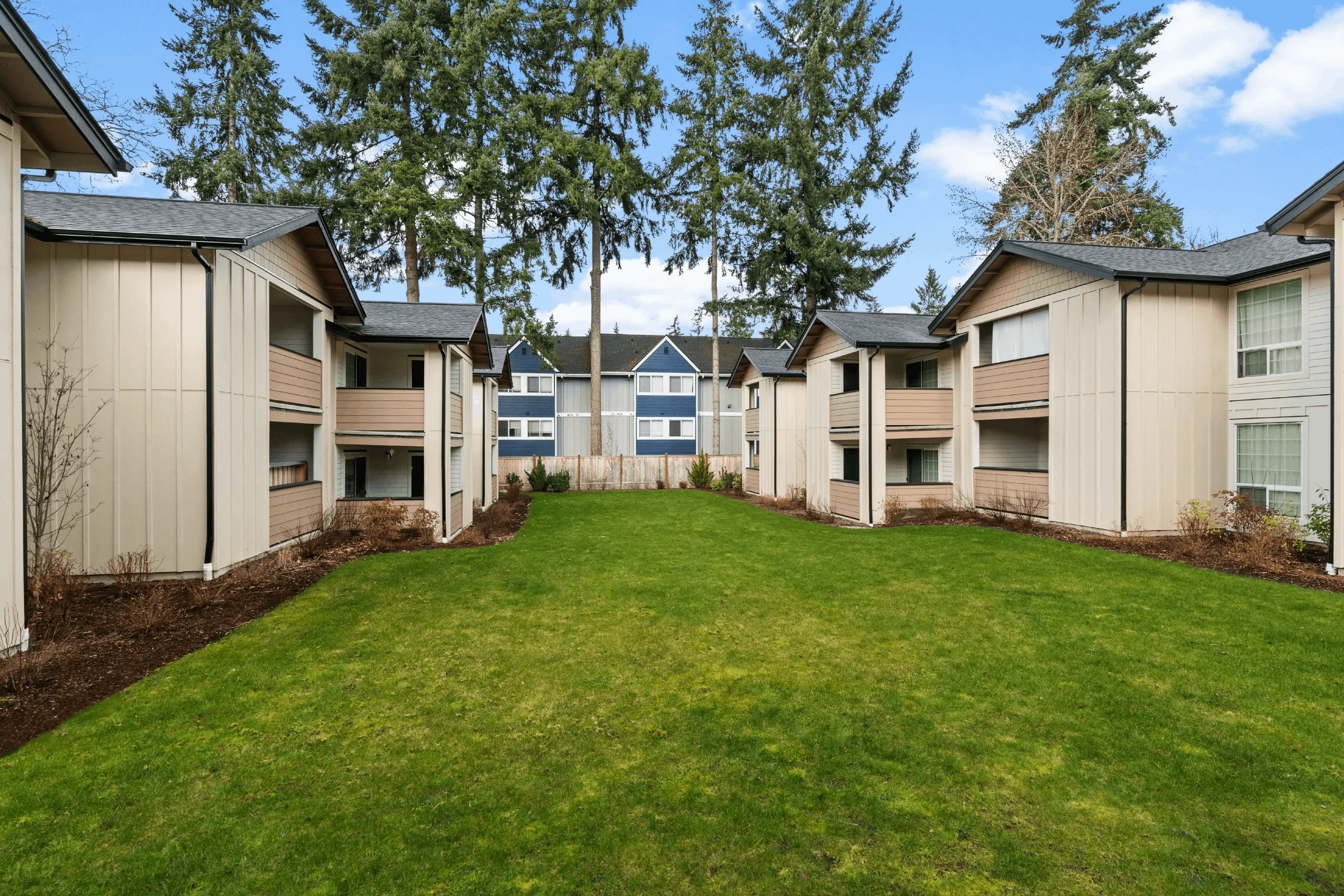 Charming apartment complex nestled in nature with lush green lawns and elegant modern architecture.
