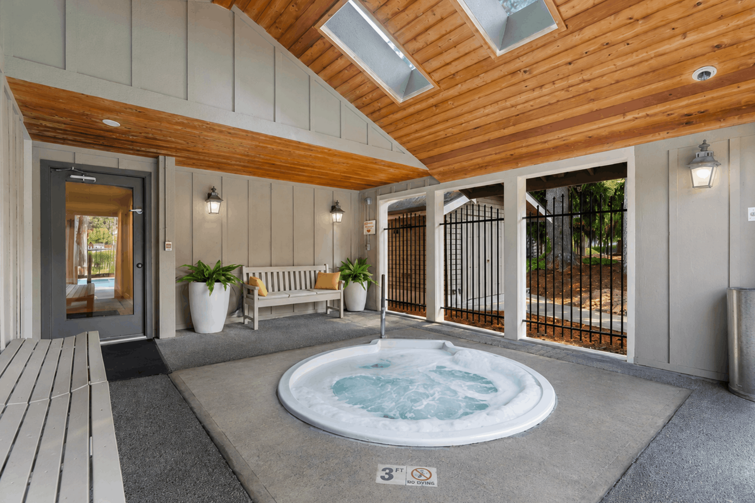 Inviting indoor spa area featuring a cozy jacuzzi with skylights, elegant wood-panel ceiling, and stylish seating for relaxation.