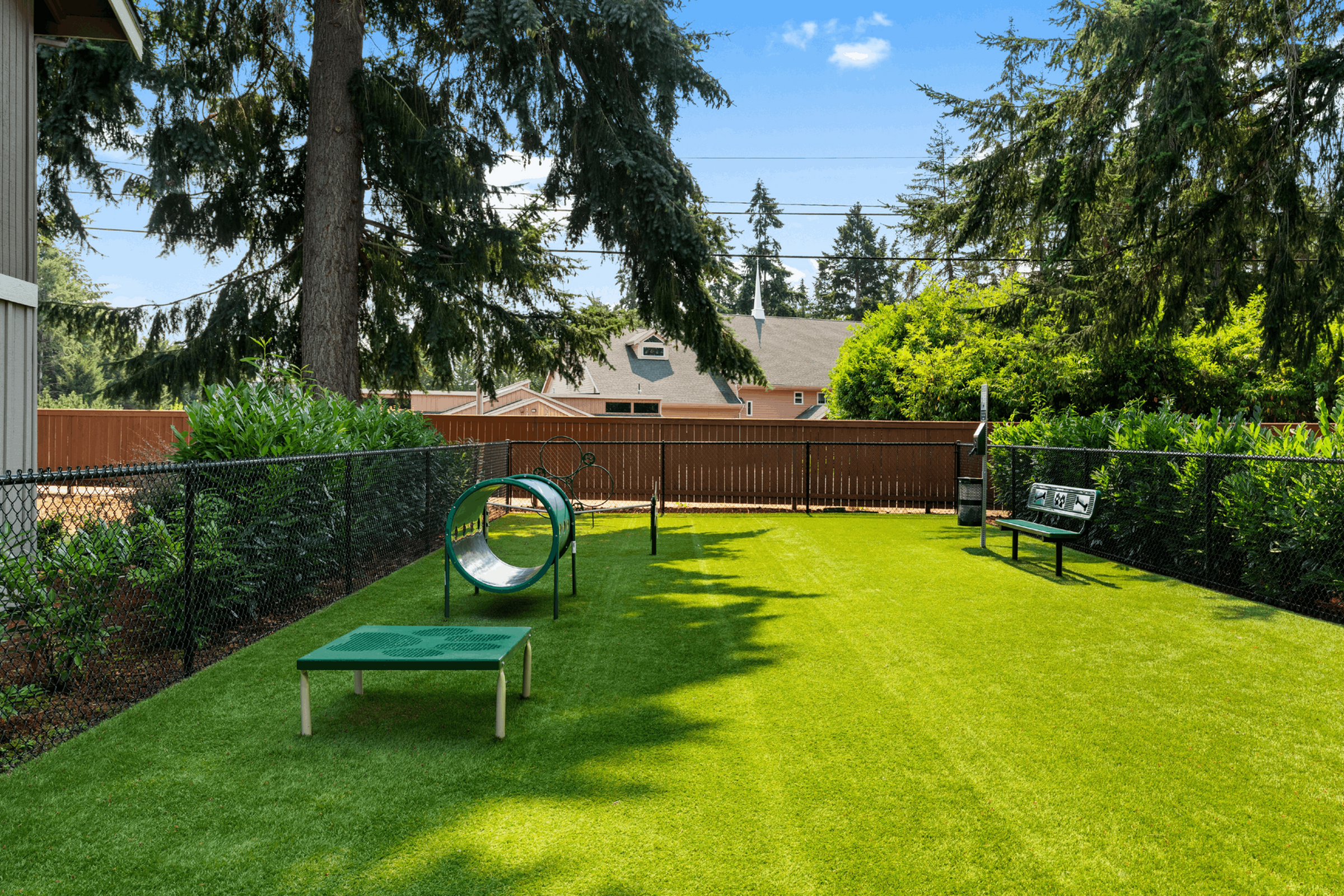 Charming fenced backyard featuring lush green grass, mature trees, and a cozy bench perfect for relaxation.