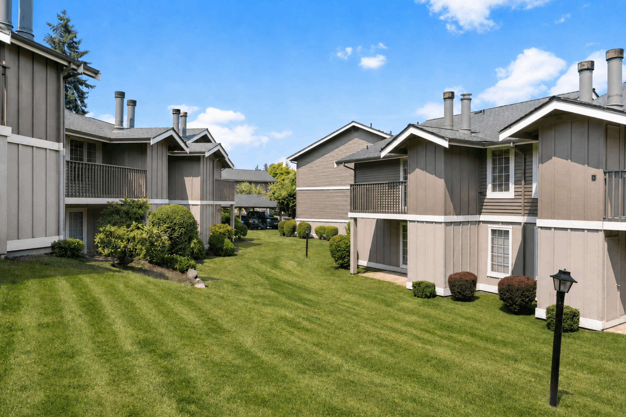 Charming apartment complex with beautiful landscaping, featuring multiple balconies and surrounded by lush greenery.