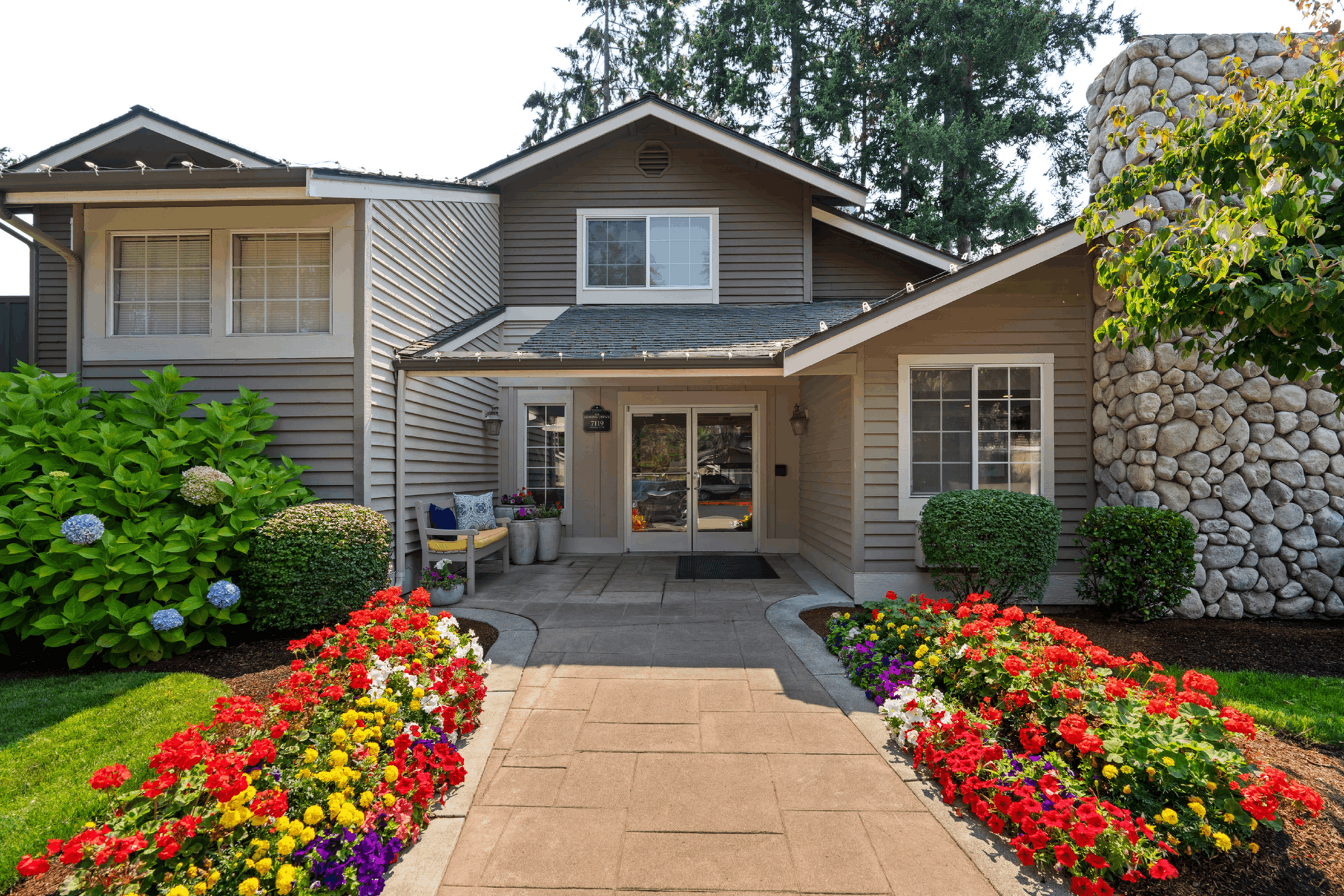 Charming front view of a well-maintained home with vibrant flower garden and welcoming entrance.