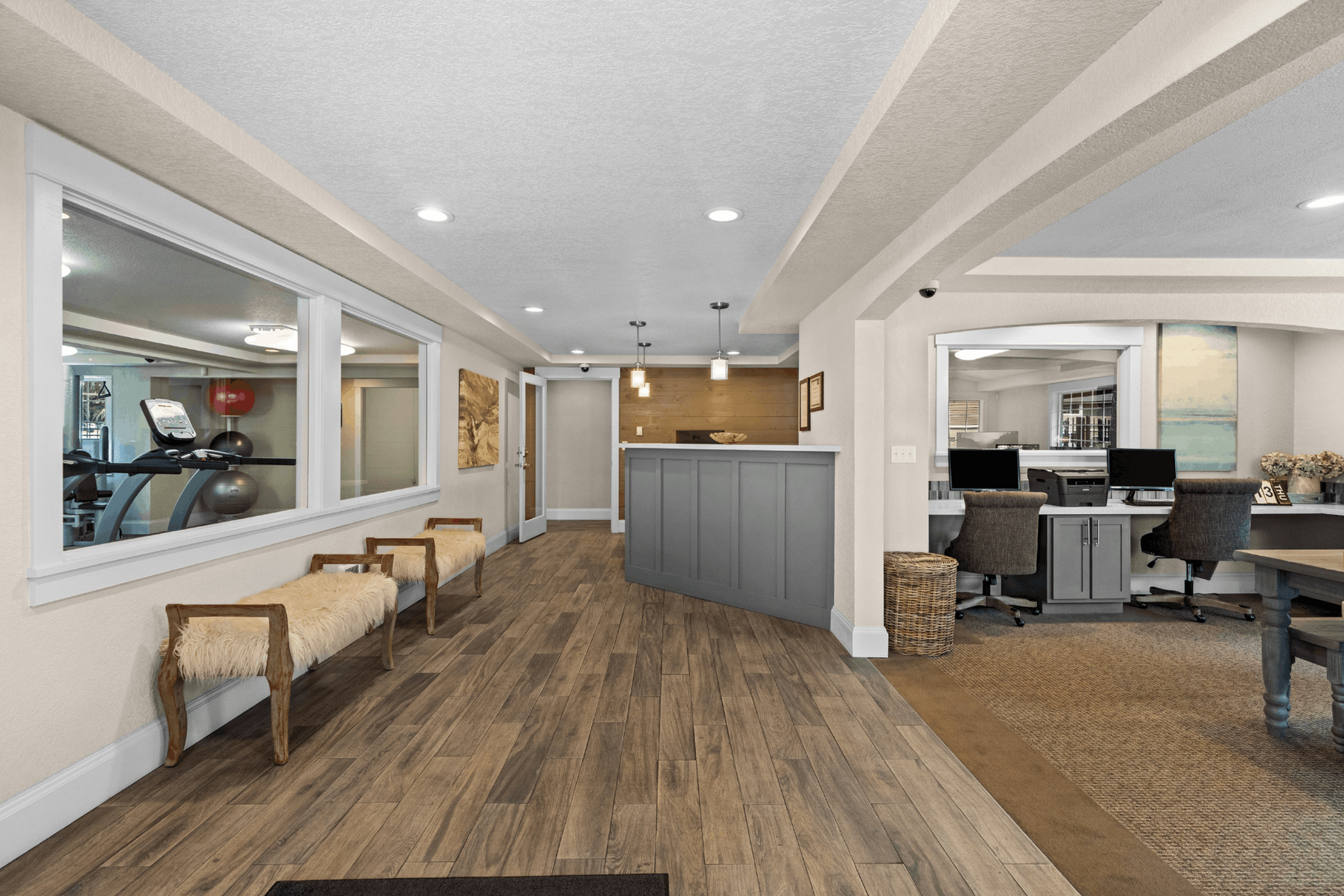 Inviting apartment lobby featuring modern design, stylish seating, and well-lit workspace with elegant wood flooring.