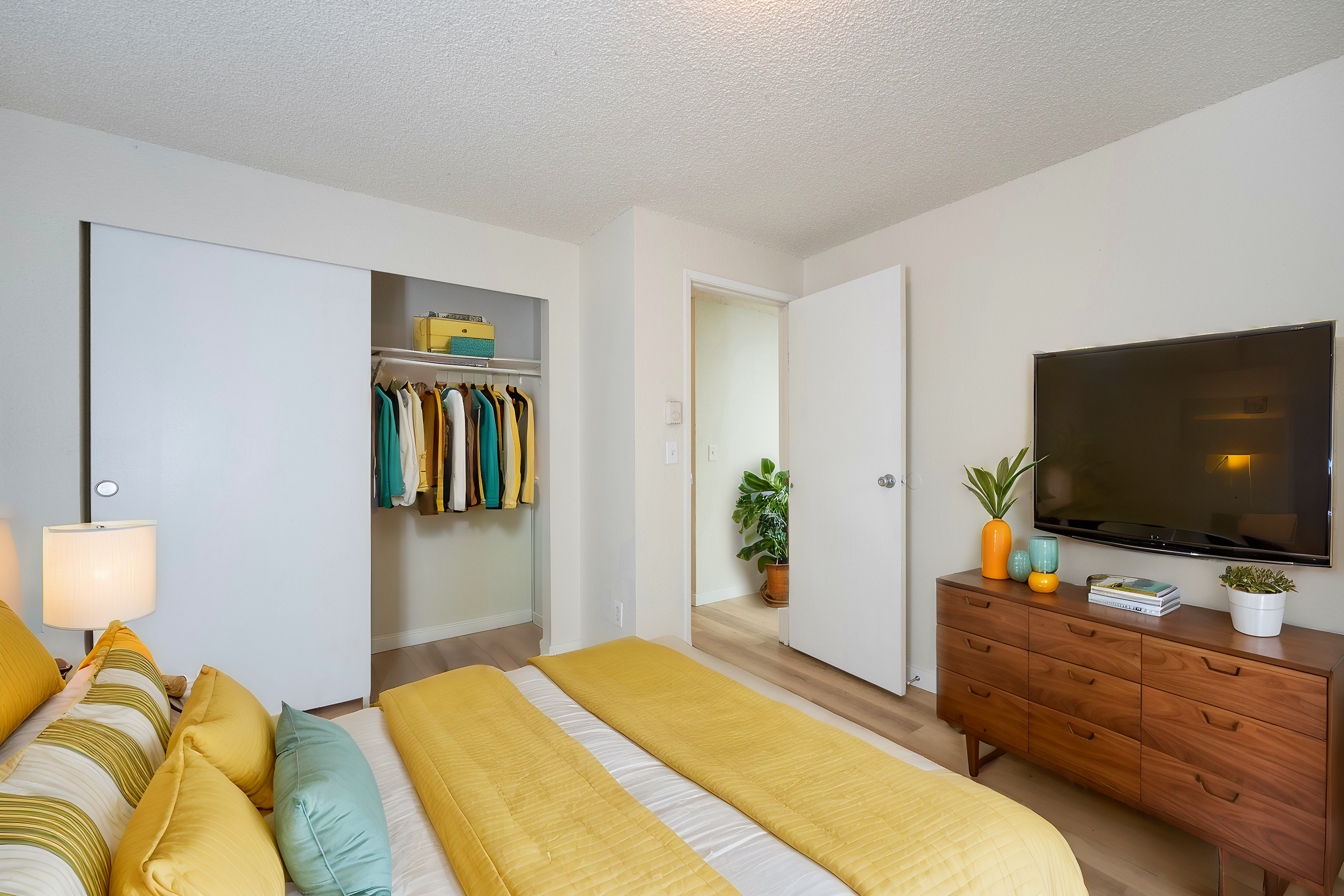 Inviting bedroom with a cozy bed, vibrant decor, and a sleek dresser with a TV.