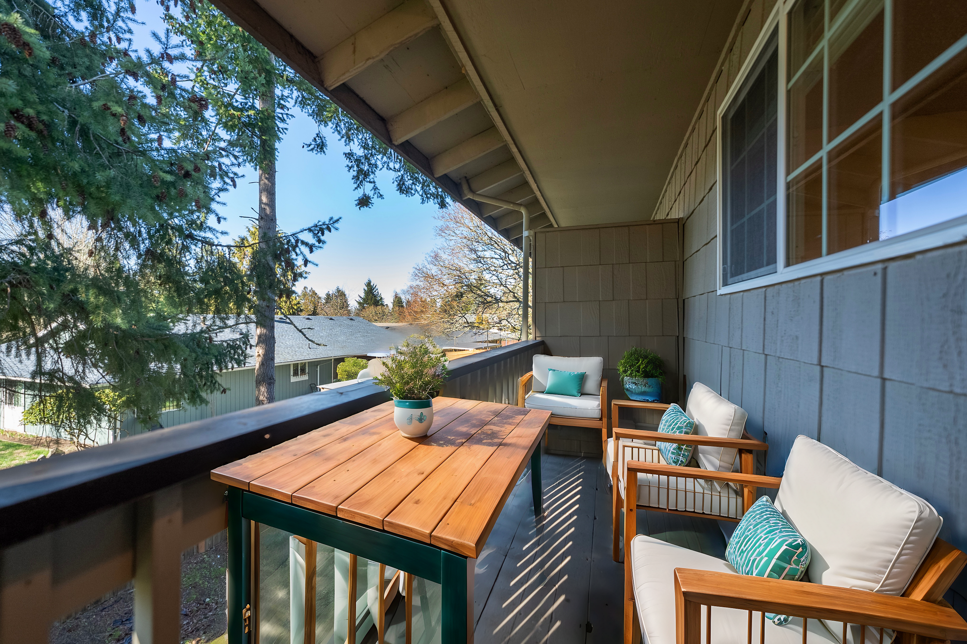 Inviting balcony with wooden furniture and lush greenery, offering peaceful views.