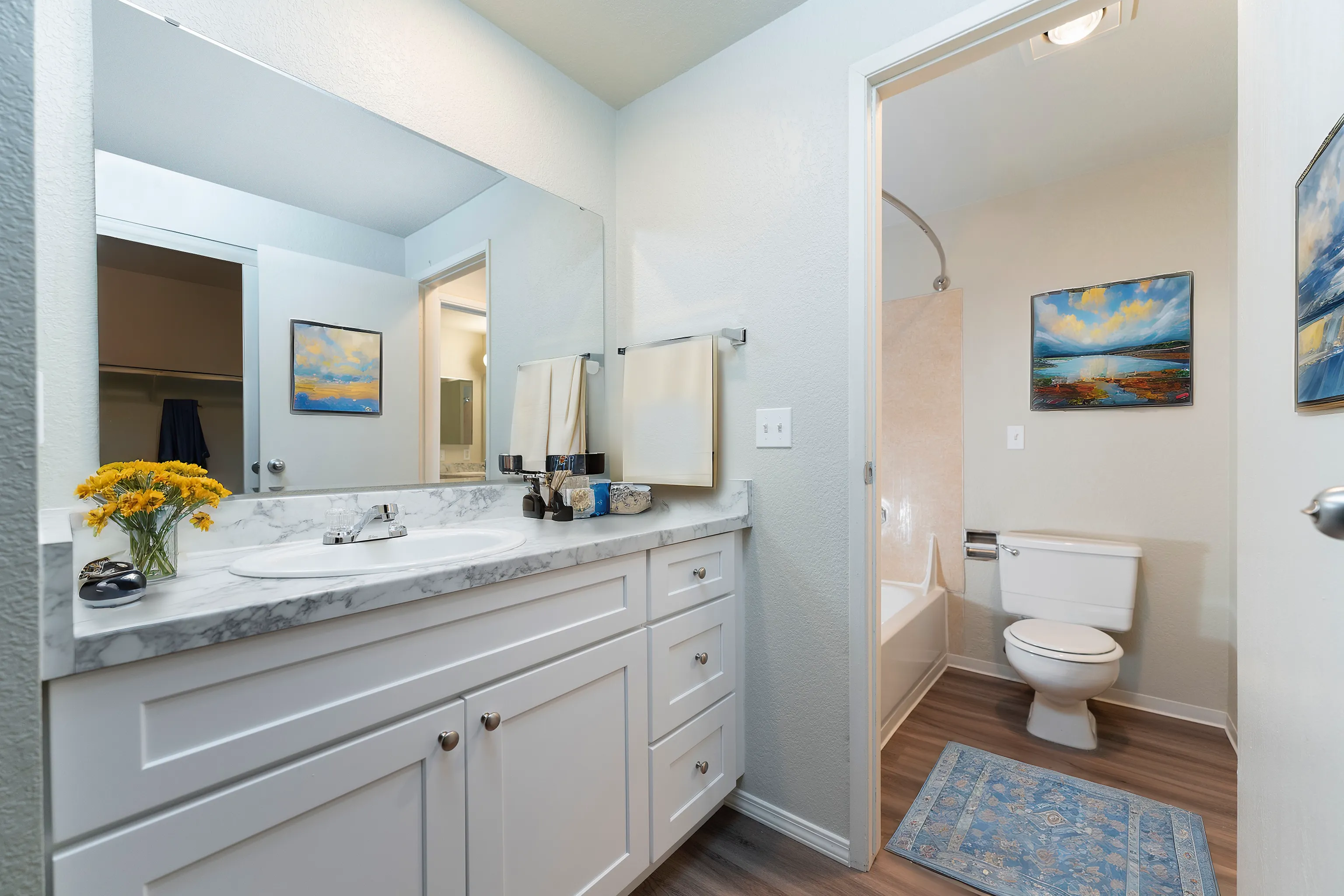 Bright and modern bathroom with marble countertop, elegant sink, and framed artwork.