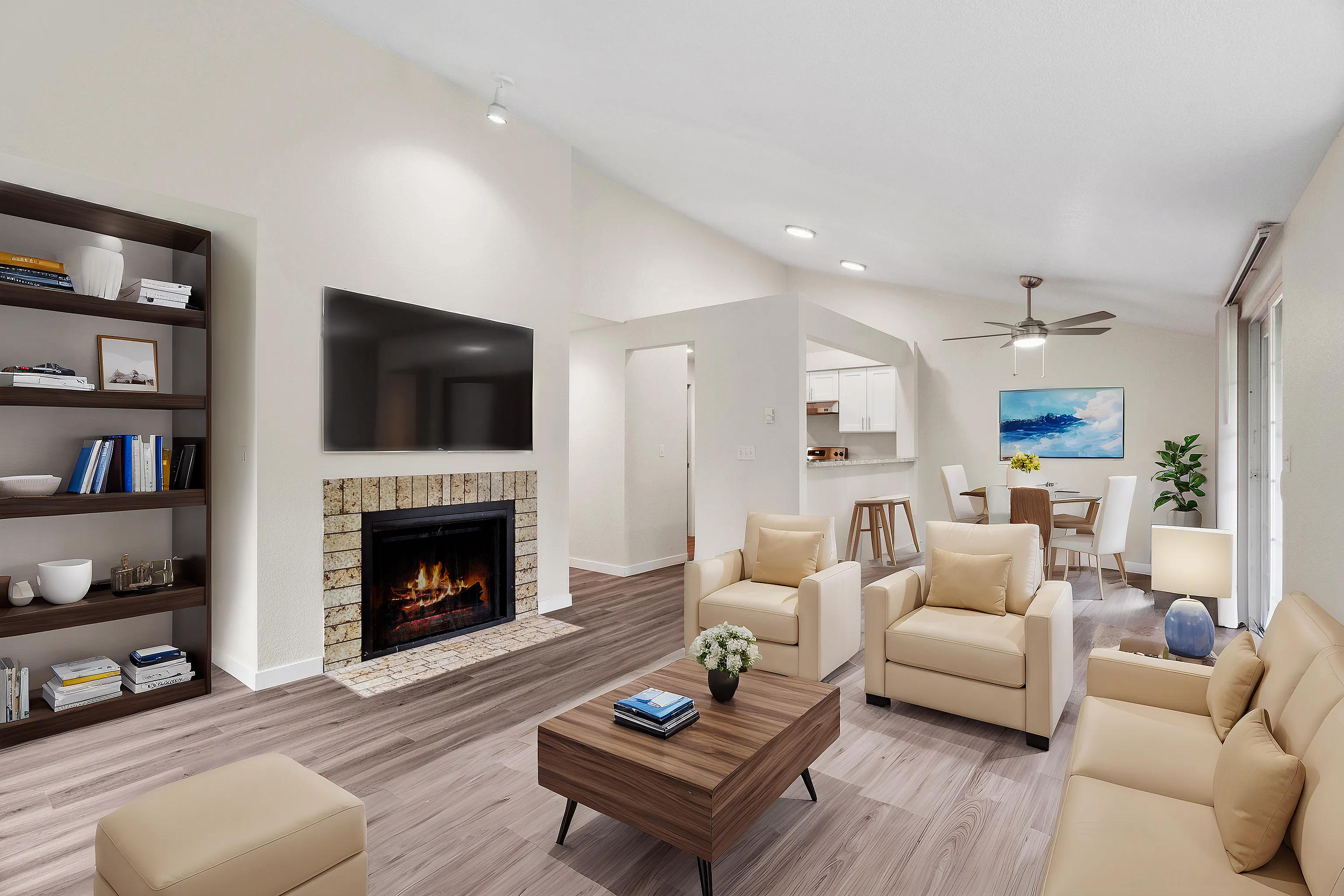 Bright modern living room with elegant beige furniture, a cozy fireplace, and open access to dining area and kitchen.
