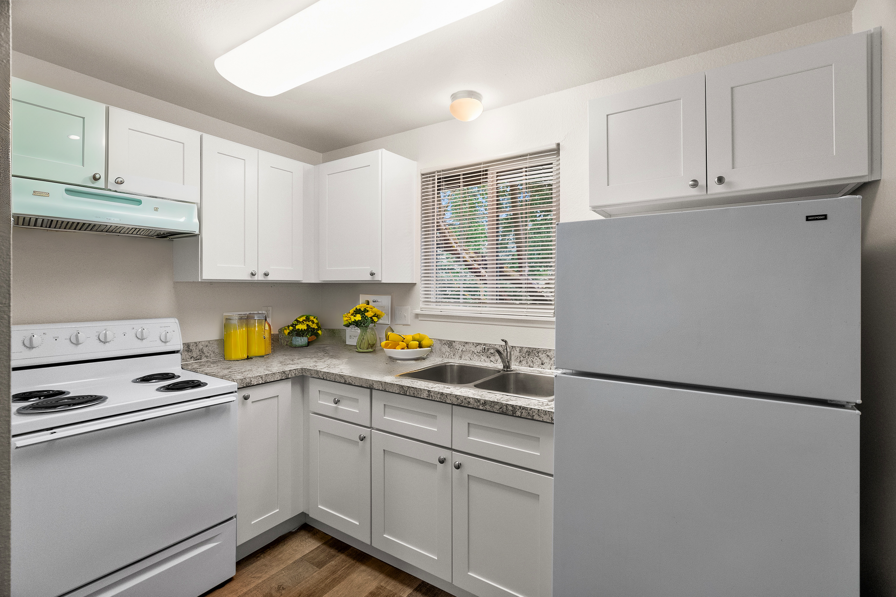 Bright kitchen with modern white cabinets, granite countertops, and stainless appliances.