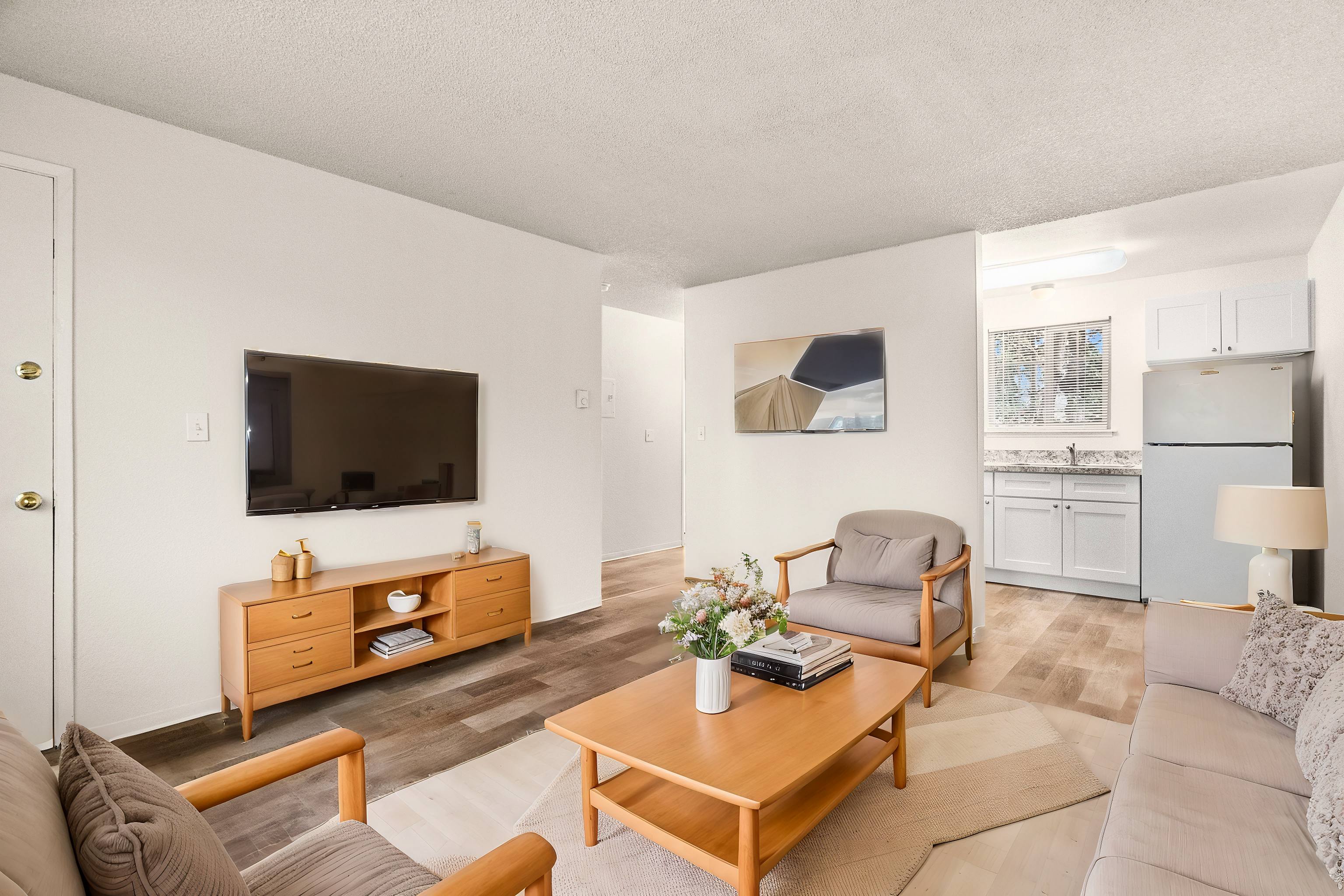 Inviting living room with stylish furniture, flat-screen TV, and an open view to the kitchen.