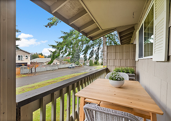 Cozy balcony with wooden table and chairs overlooking a scenic neighborhood street.
