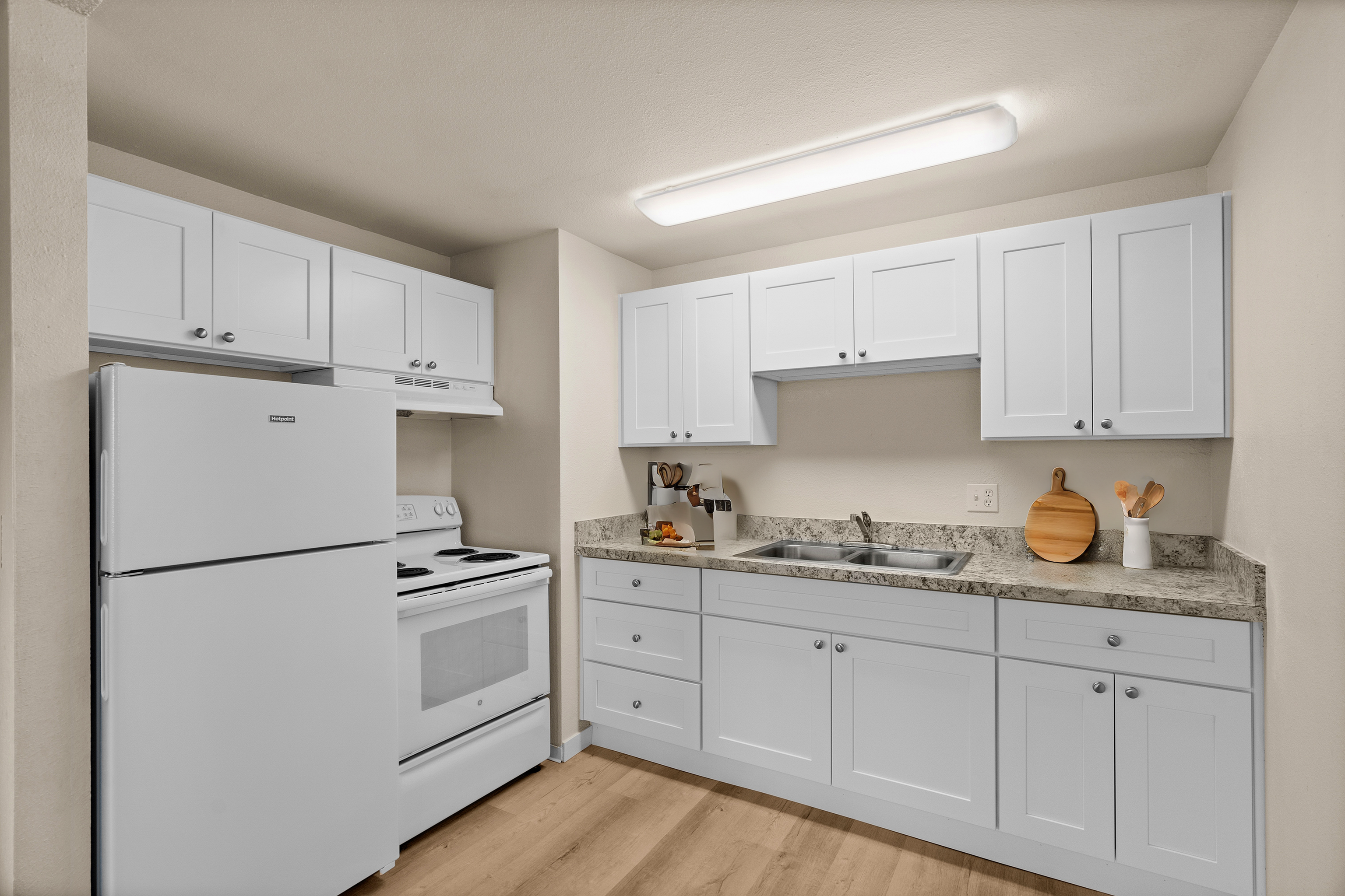 Bright kitchen with white cabinetry, modern appliances, and marble countertops.