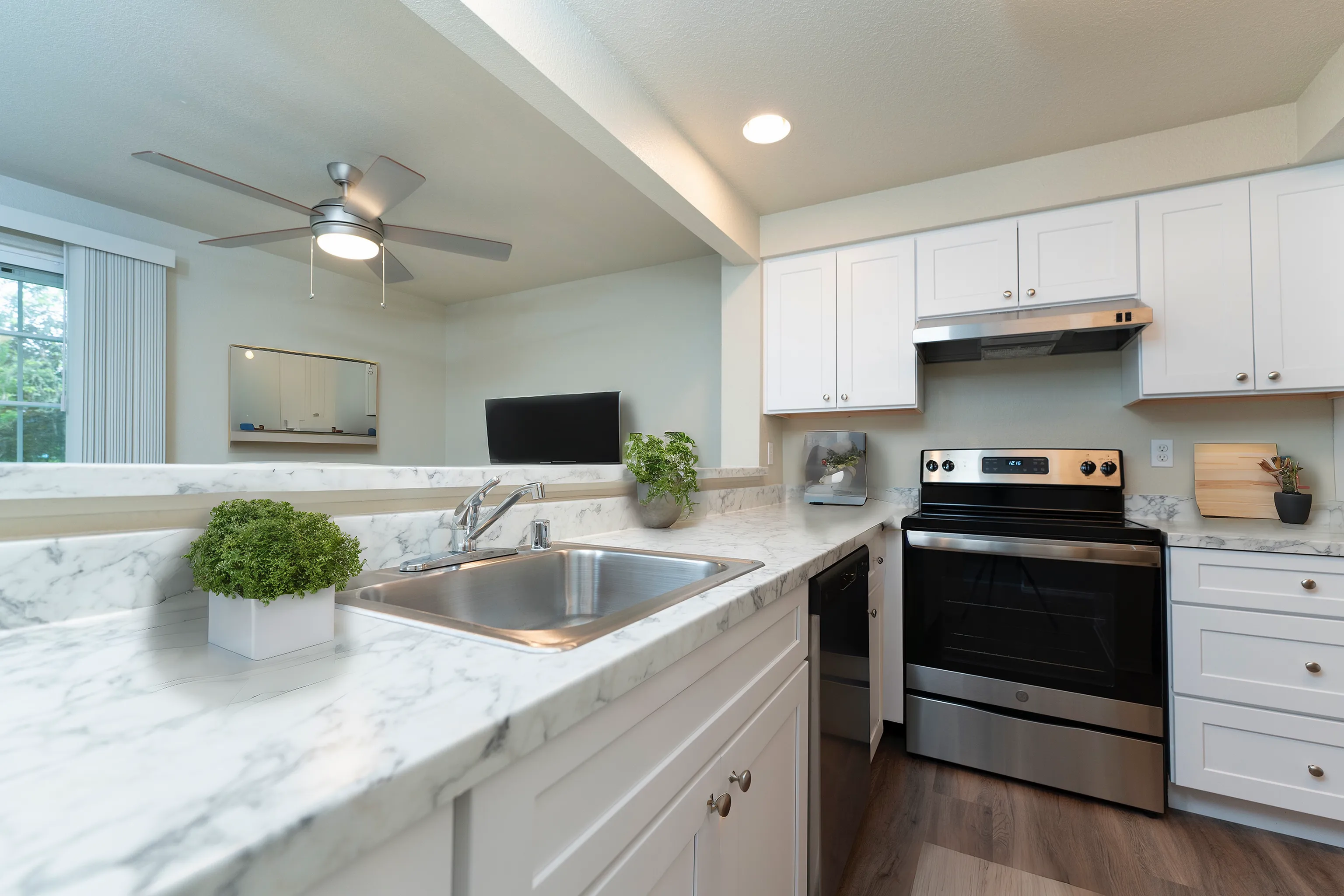 Contemporary kitchen featuring marble countertops, stainless steel appliances, and elegant white cabinetry.
