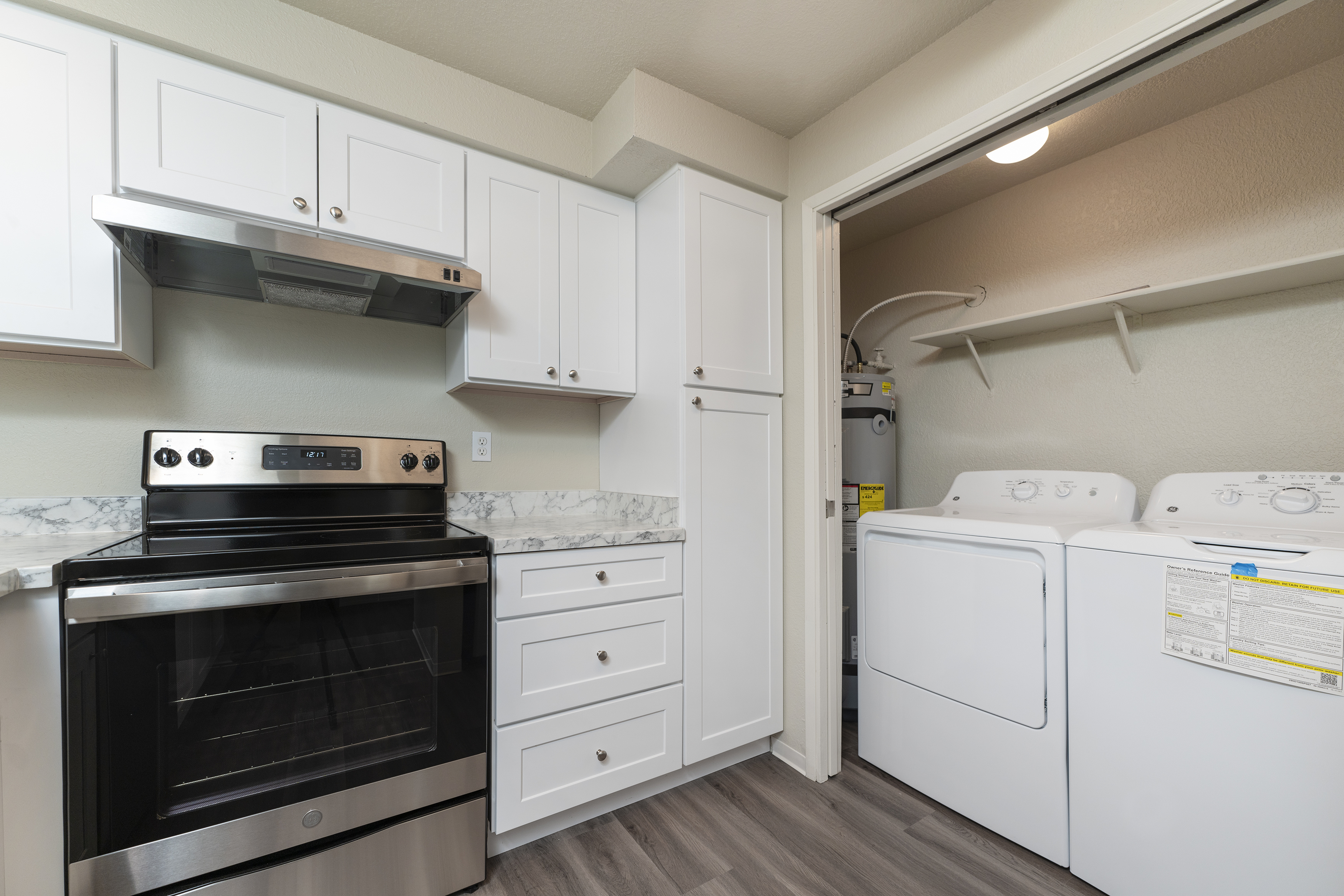Modern kitchen with stainless steel appliances and adjacent laundry area.