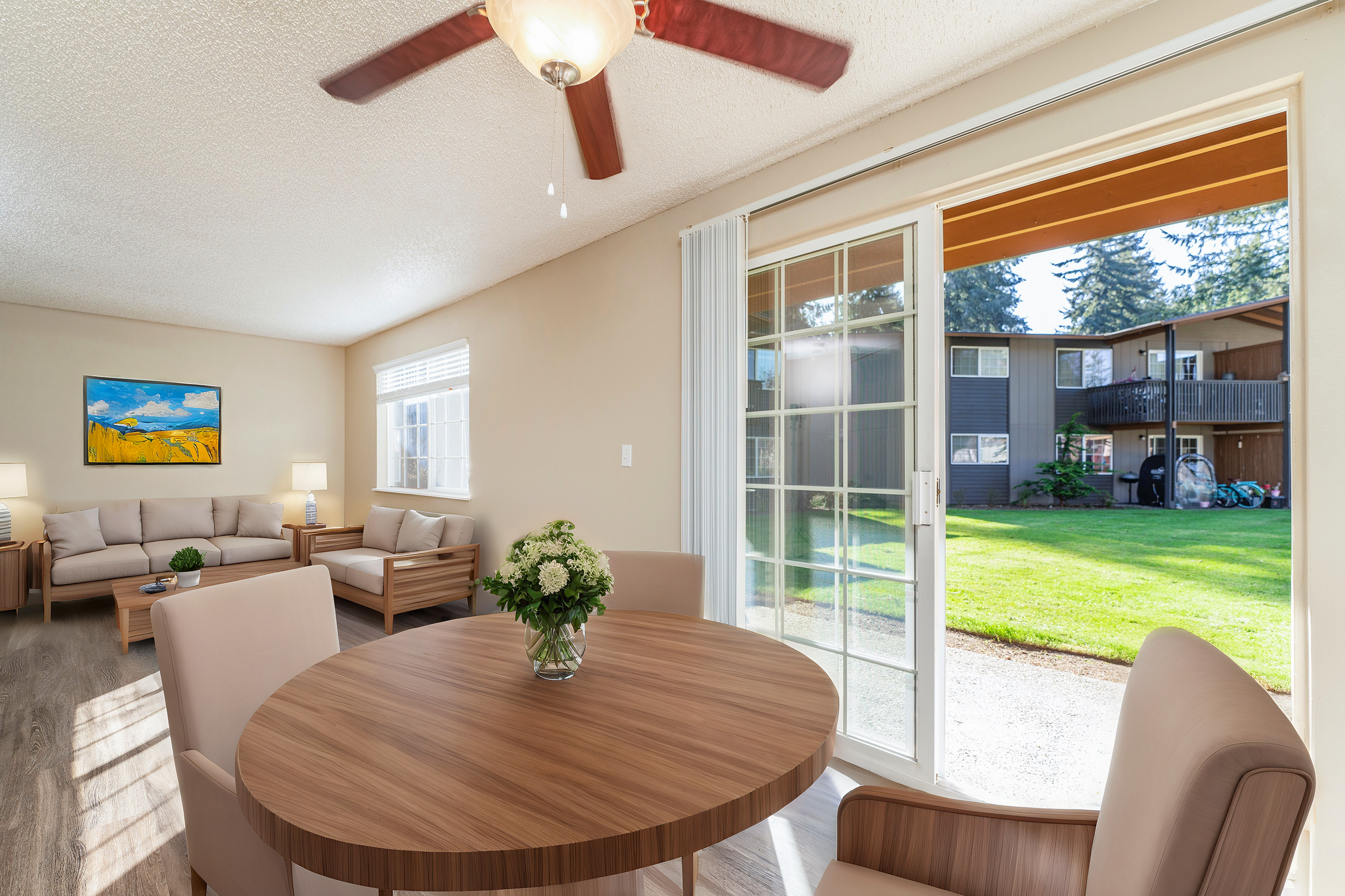 Spacious living room with modern furnishings, large windows, and a view of the green outdoor area.