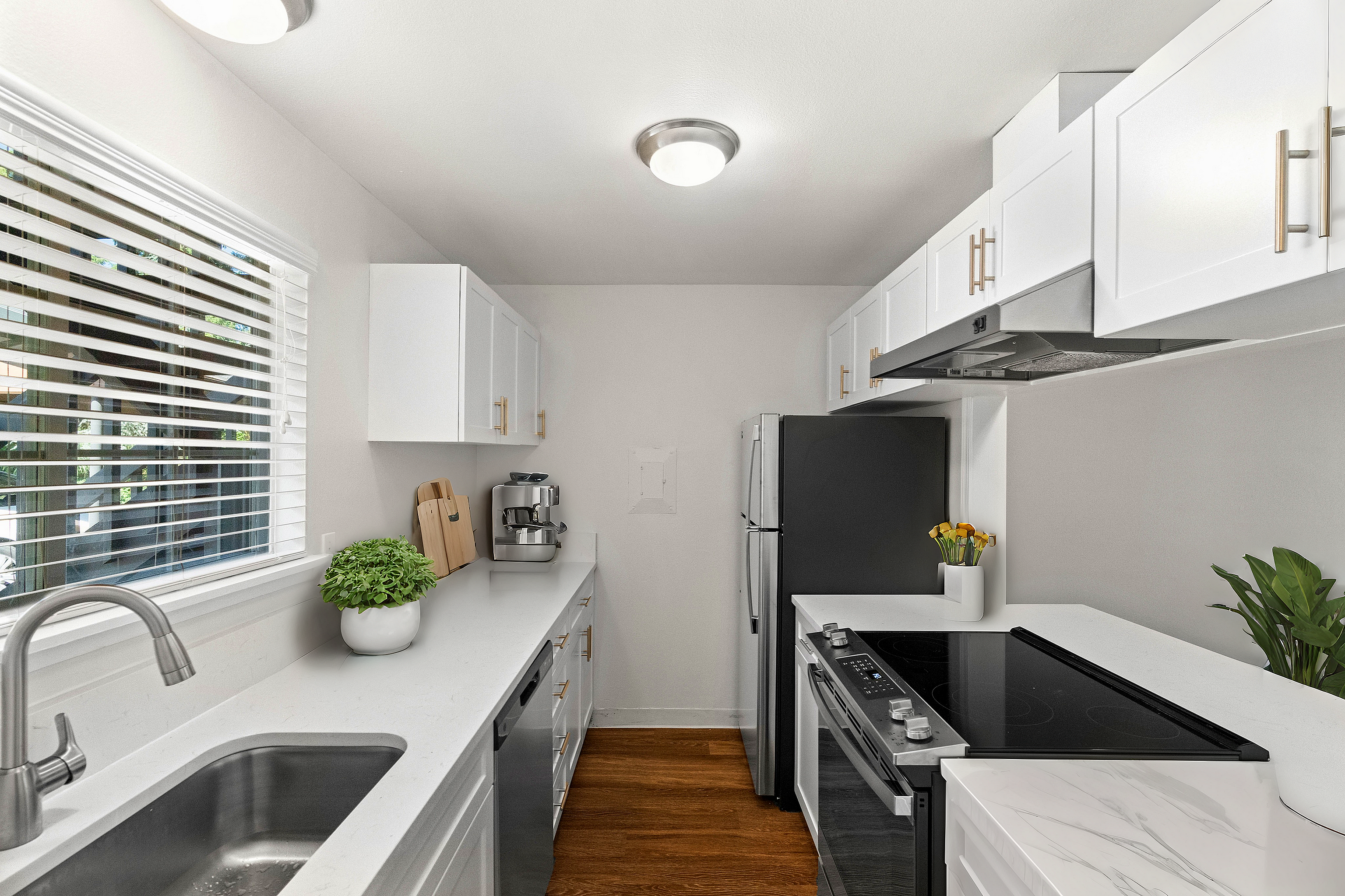Bright and stylish modern kitchen featuring white cabinetry, stainless steel appliances, and natural light.