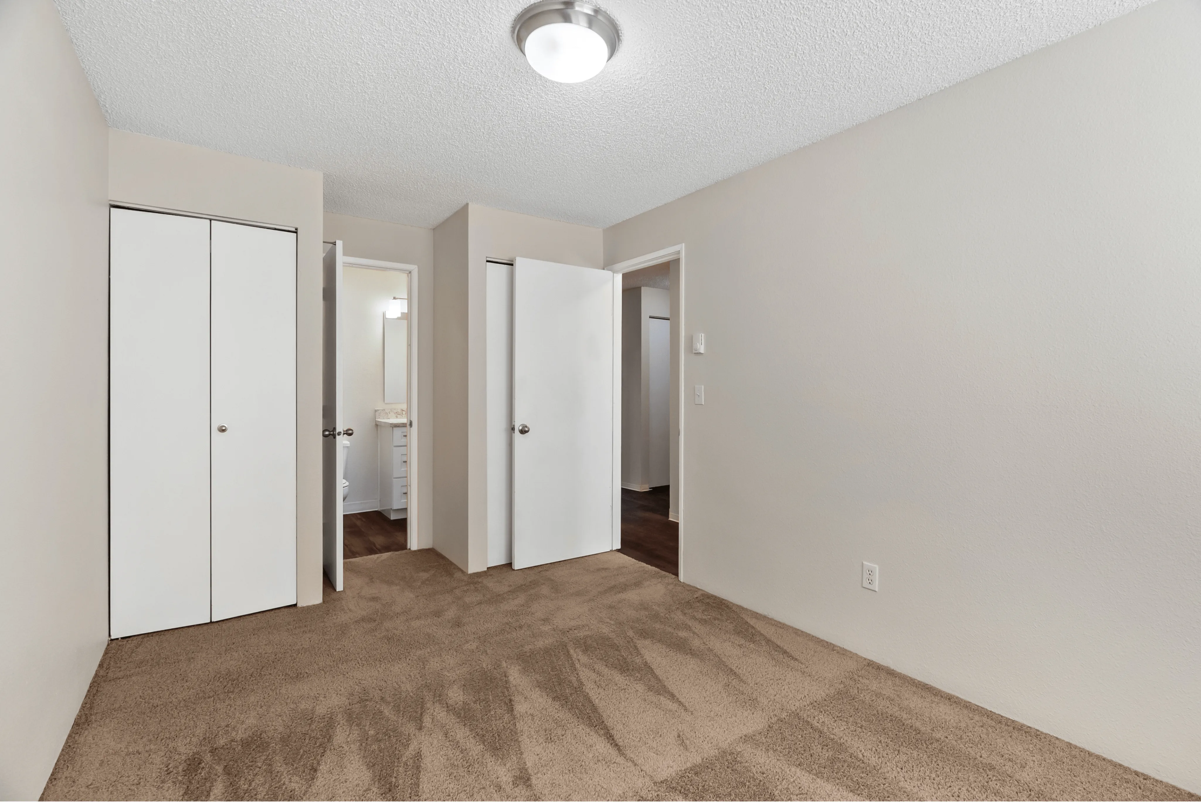 Bright and roomy bedroom with plush carpet, closet, and neutral walls.