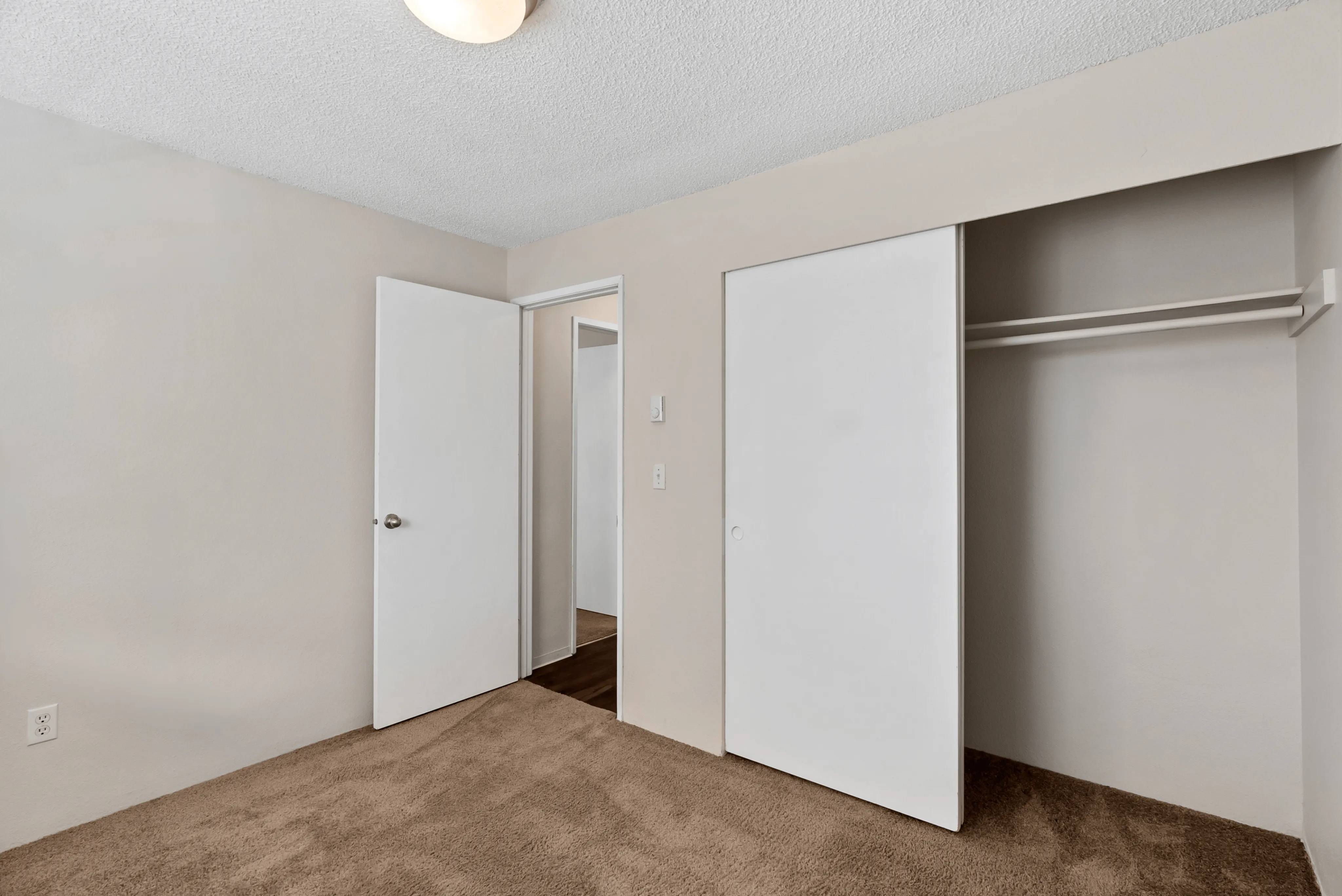 Calm bedroom featuring a textured ceiling, plush carpet, and a built-in closet with sliding doors.