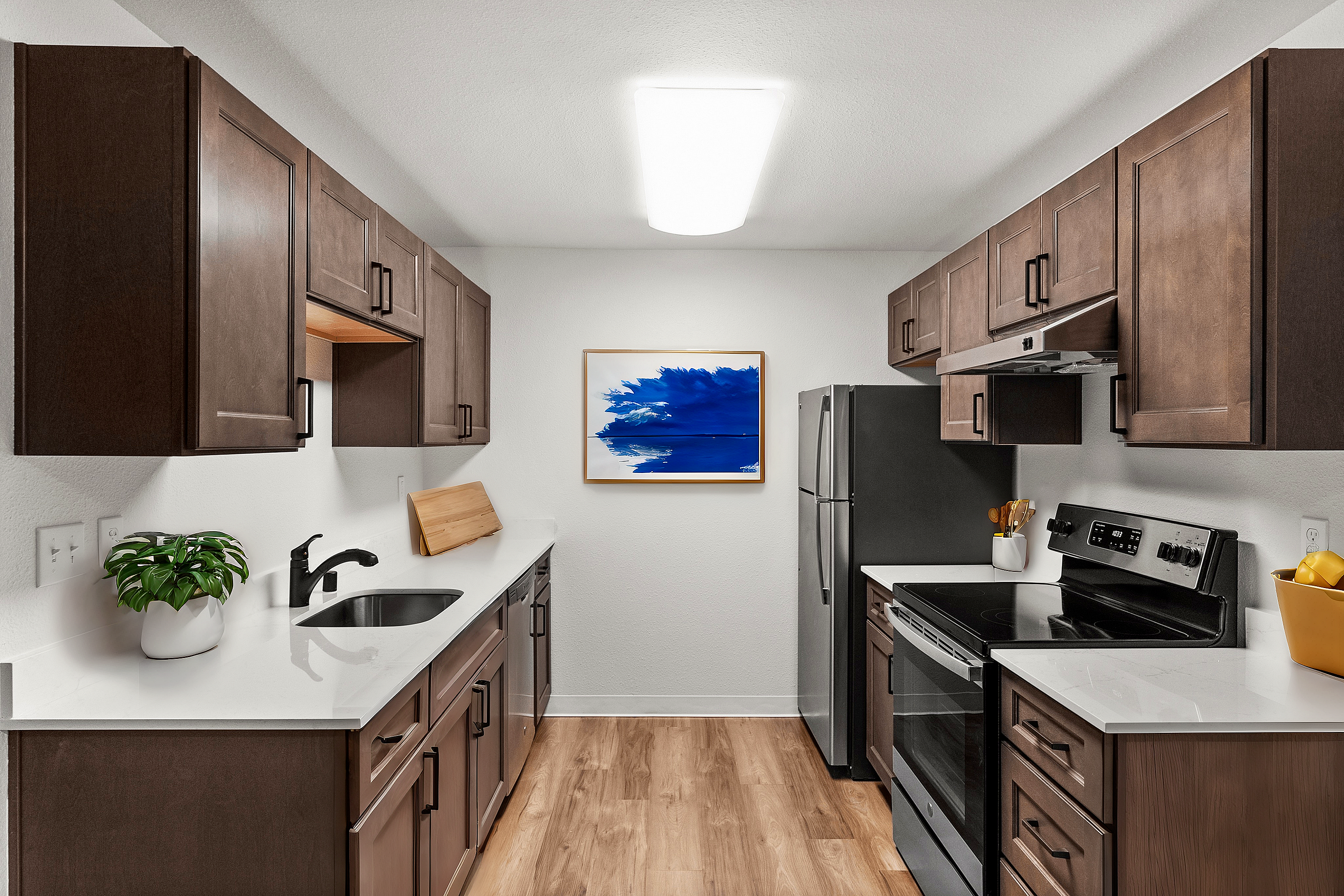 Elegant modern kitchen featuring dark wood cabinets, stainless steel appliances, and a bright abstract painting.