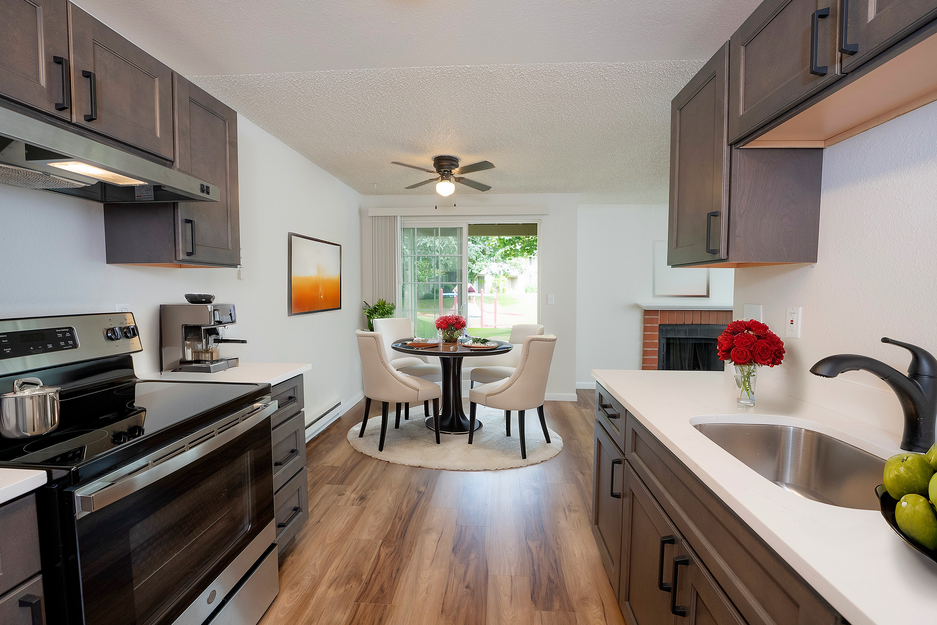 Sleek kitchen with dark cabinets, modern appliances, and an inviting dining area with elegant white chairs.