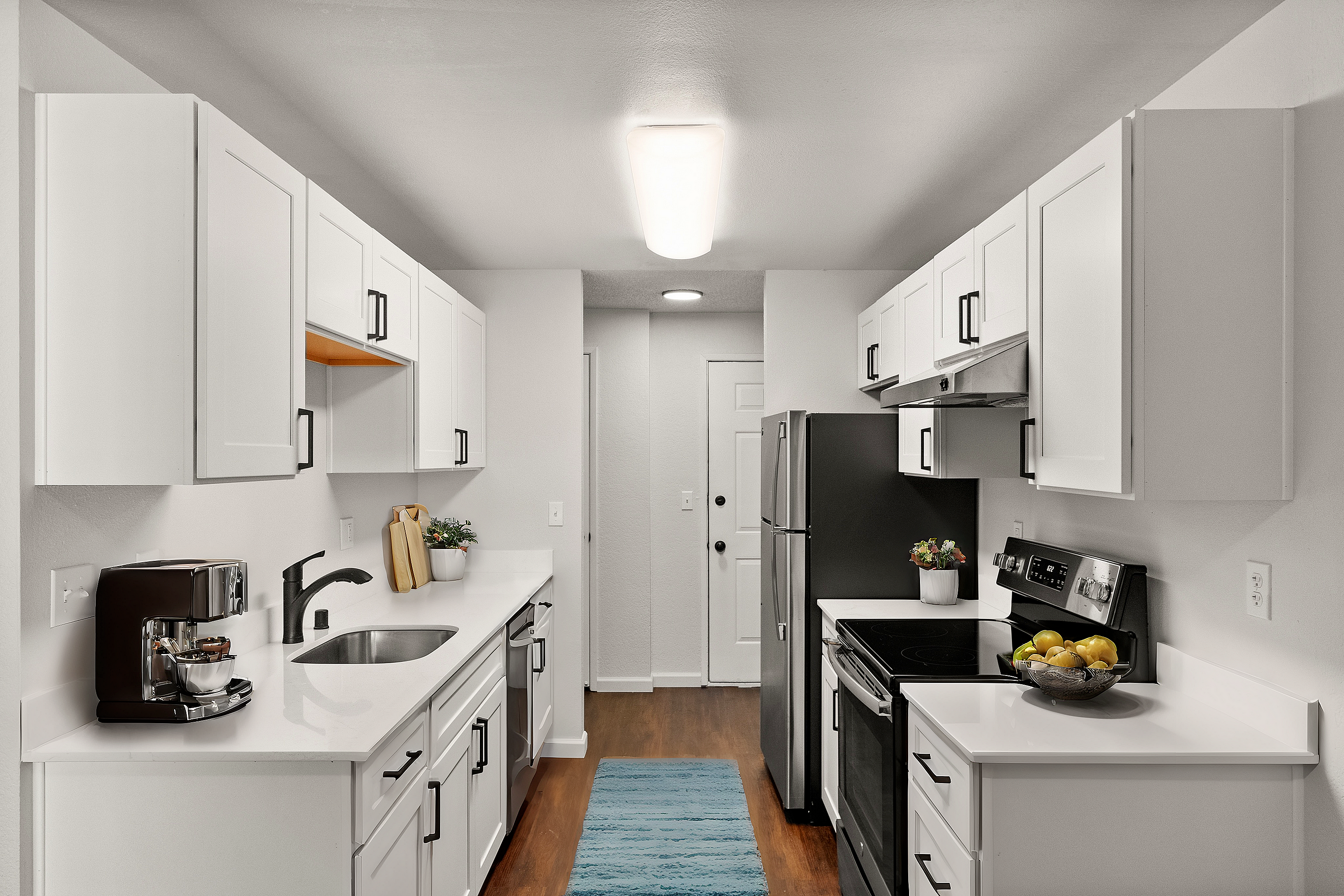 Sleek modern kitchen with white cabinetry, stainless steel appliances, and hardwood floors.