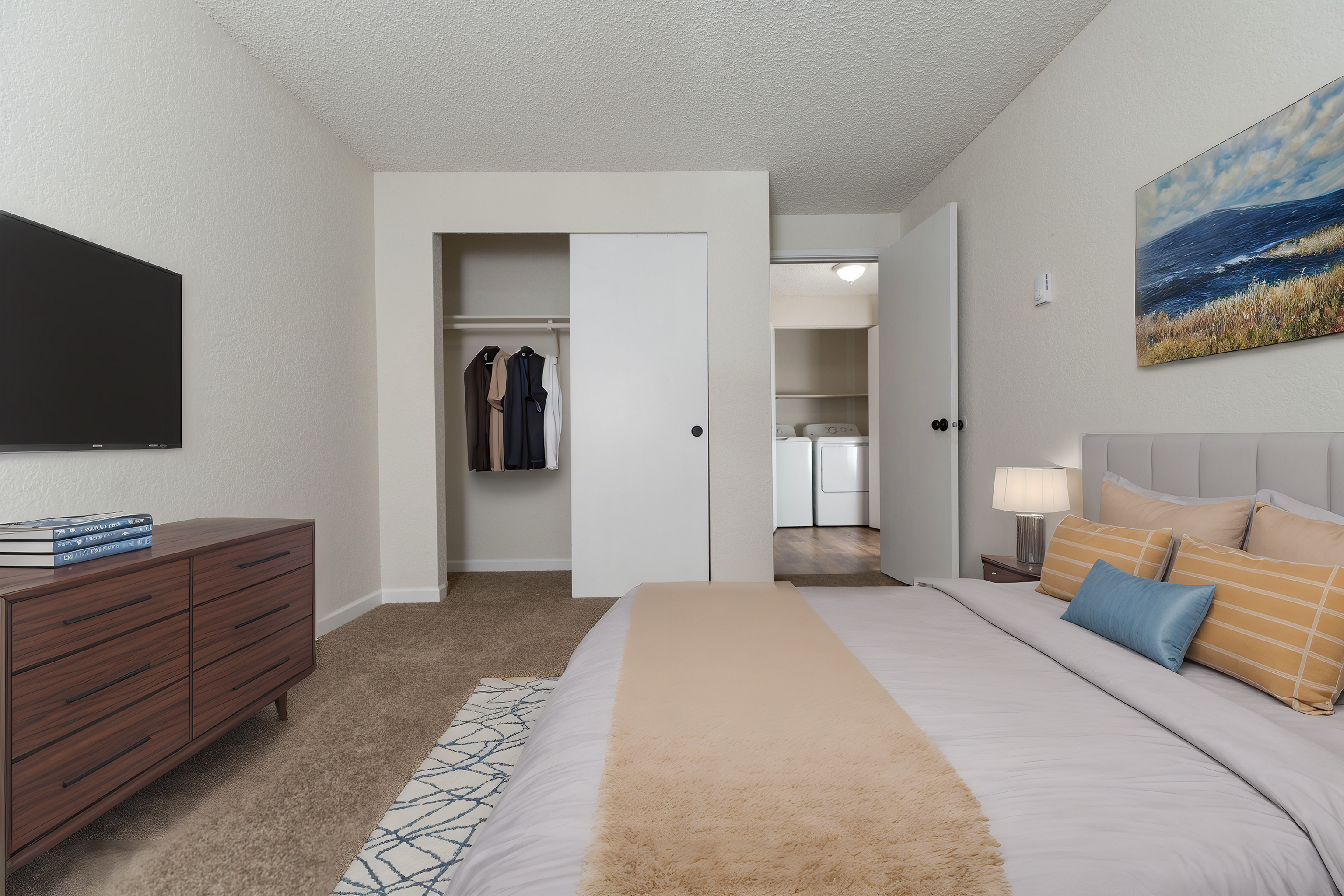 Chic bedroom featuring a cozy bed, stylish dresser, open closet, and view of a discreet laundry room.