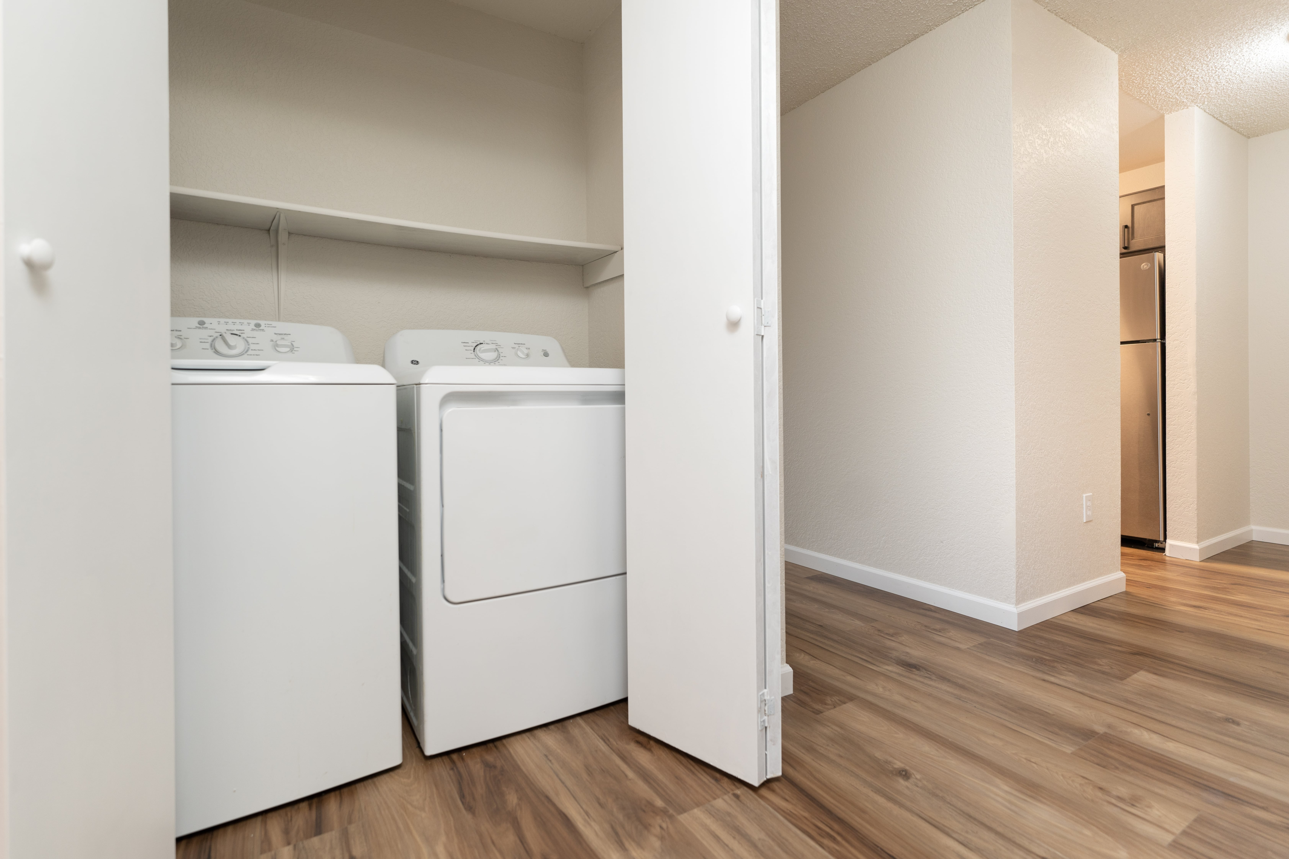 Modern laundry area with white washer and dryer and open shelving.