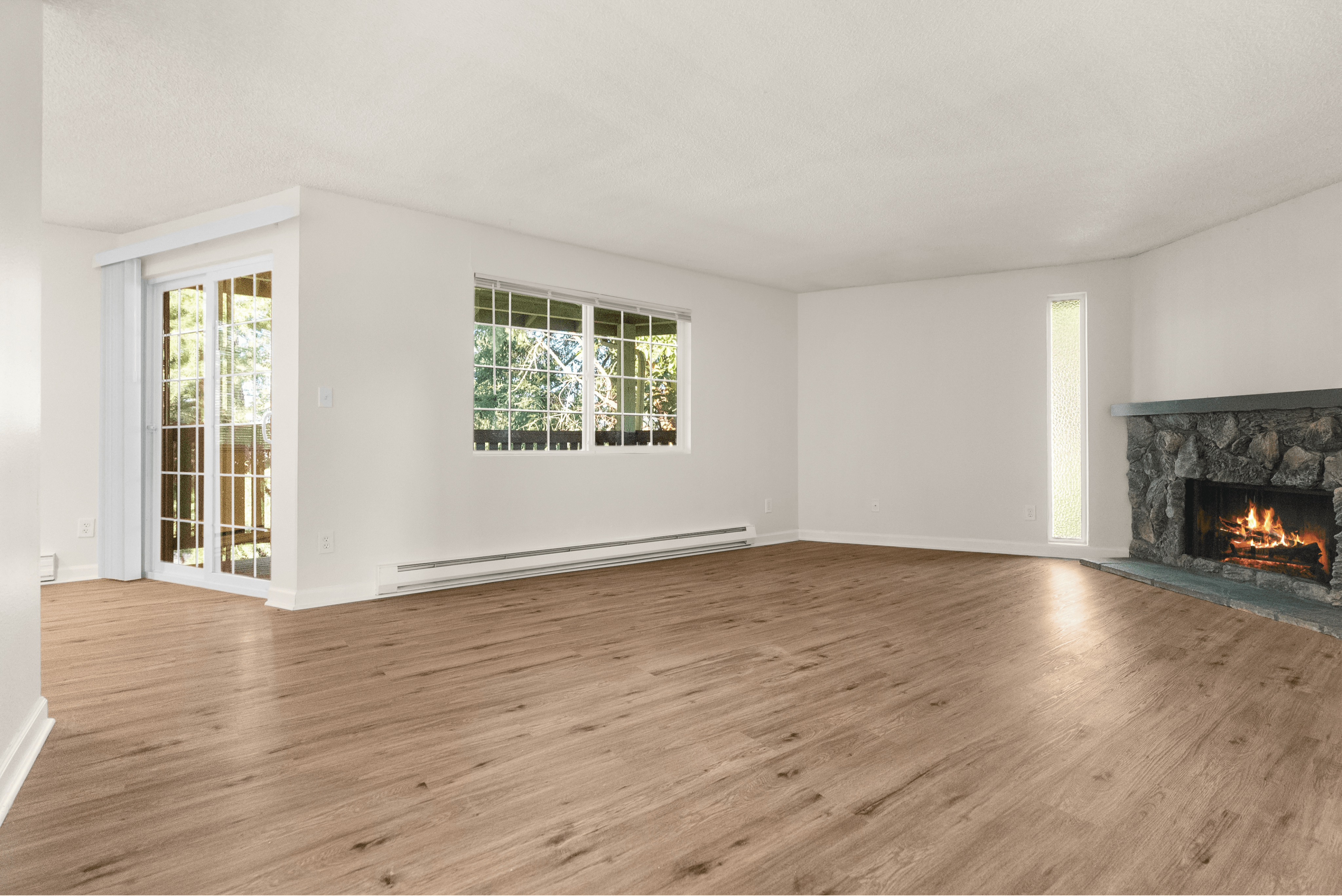 Bright, spacious living room featuring a large window, elegant wooden flooring, and cozy stone fireplace.