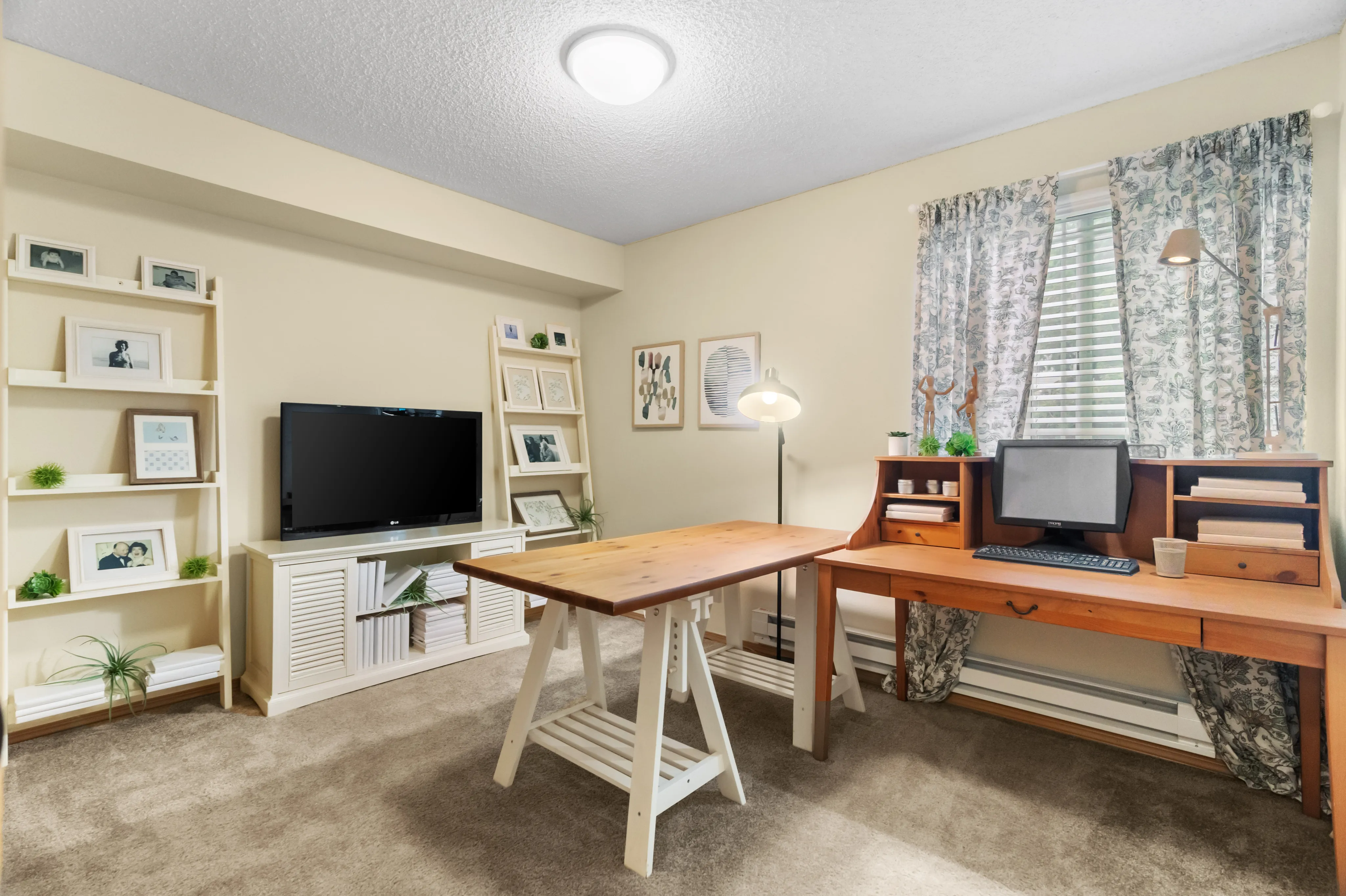 Charming home office with wooden desk, computer, TV, and decorative shelves.