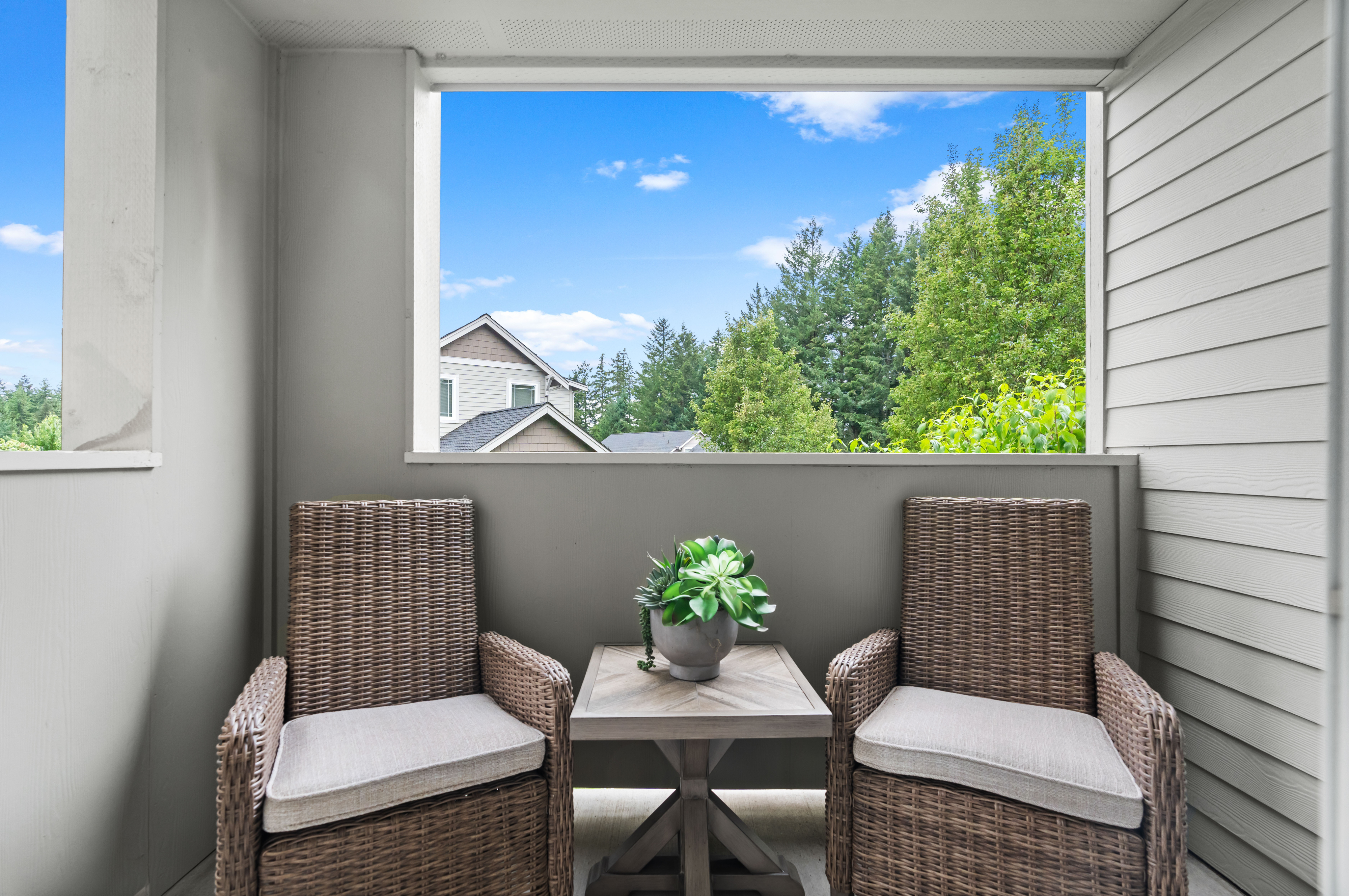 Charming outdoor patio with wicker chairs and a lush green view