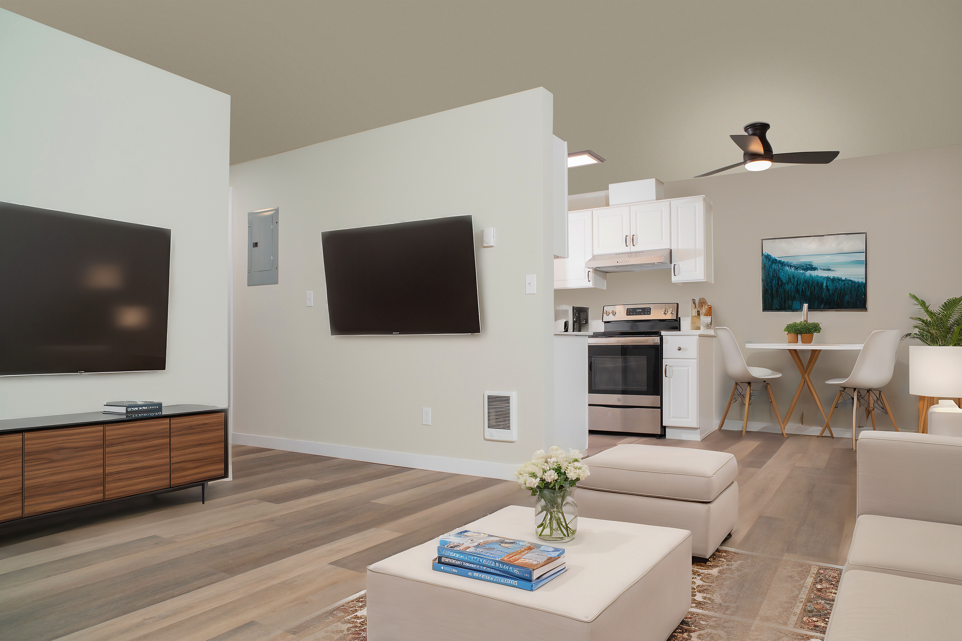 Bright living room with a wall-mounted TV, modern kitchen, and a dining area with a contemporary ceiling fan.