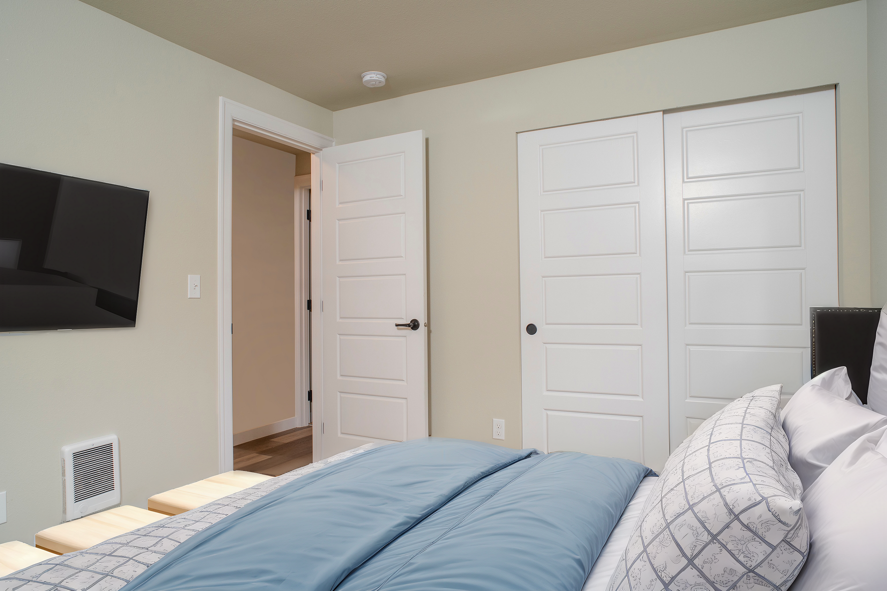 Inviting bedroom with a plush bed, elegant closet doors, and a mounted TV for relaxing evenings.