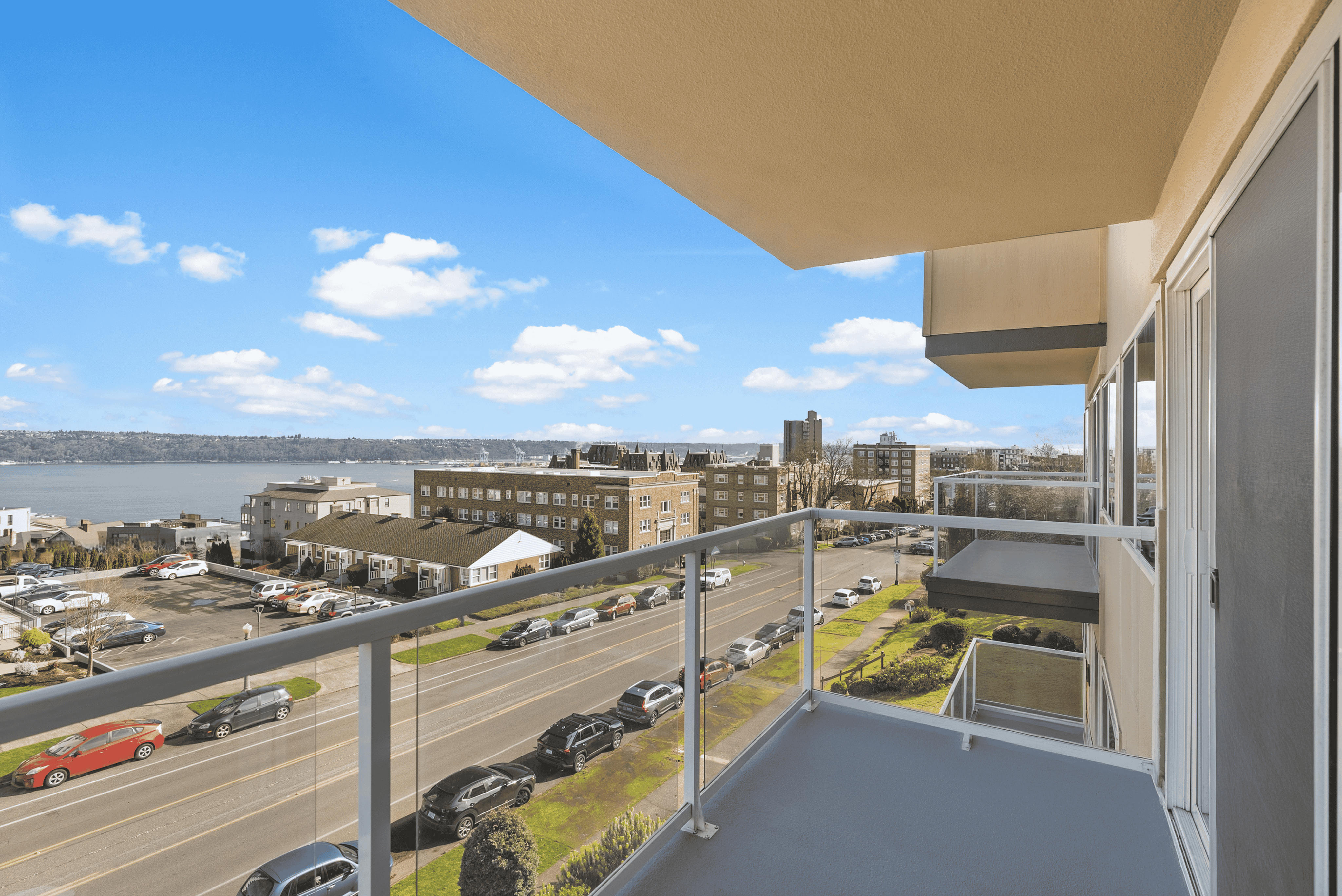 Balcony overlooking a bustling street with a view of distant waters and buildings under a clear blue sky.