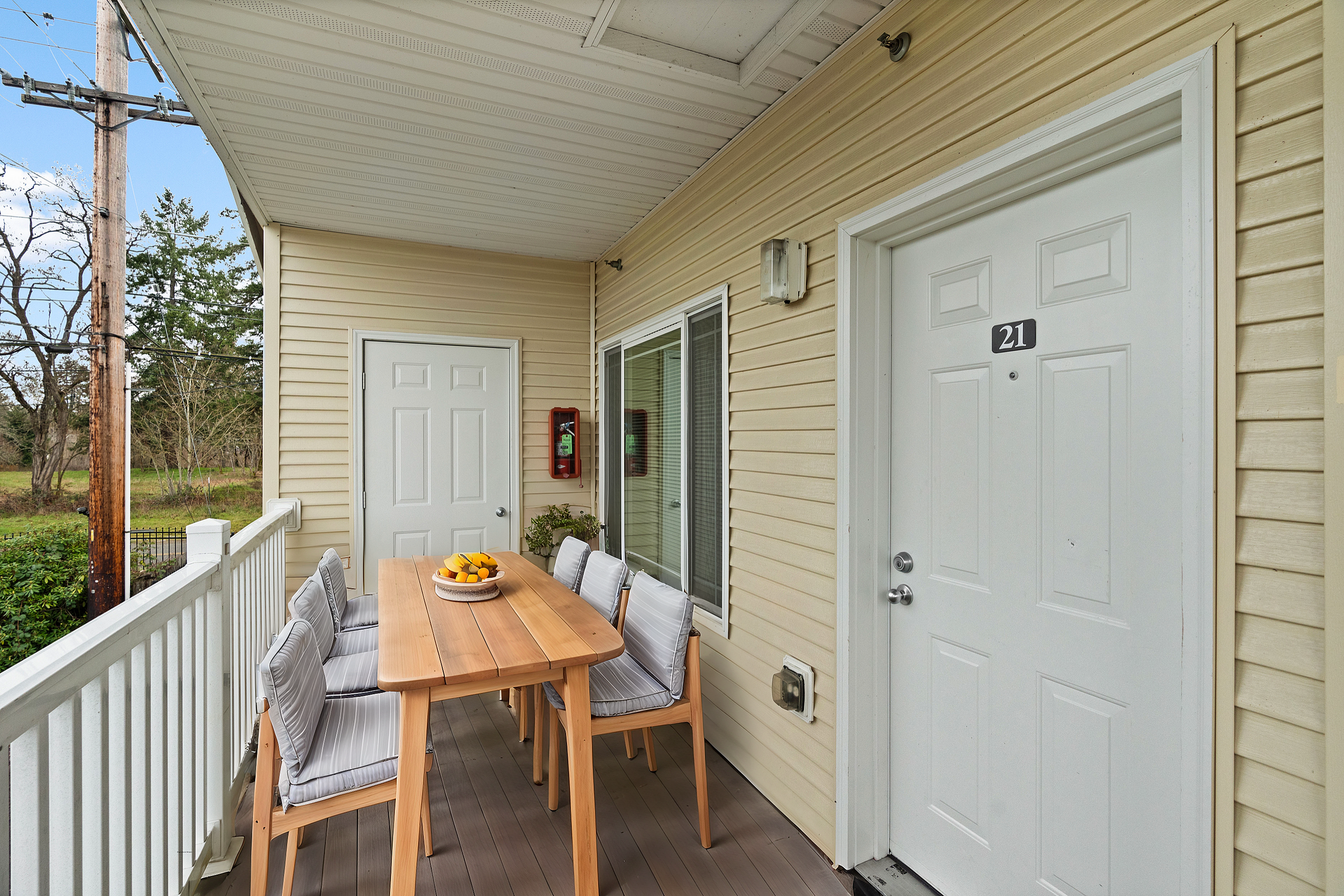 Charming outdoor patio with a wooden dining table and cozy seating, surrounded by lush greenery and serene views.