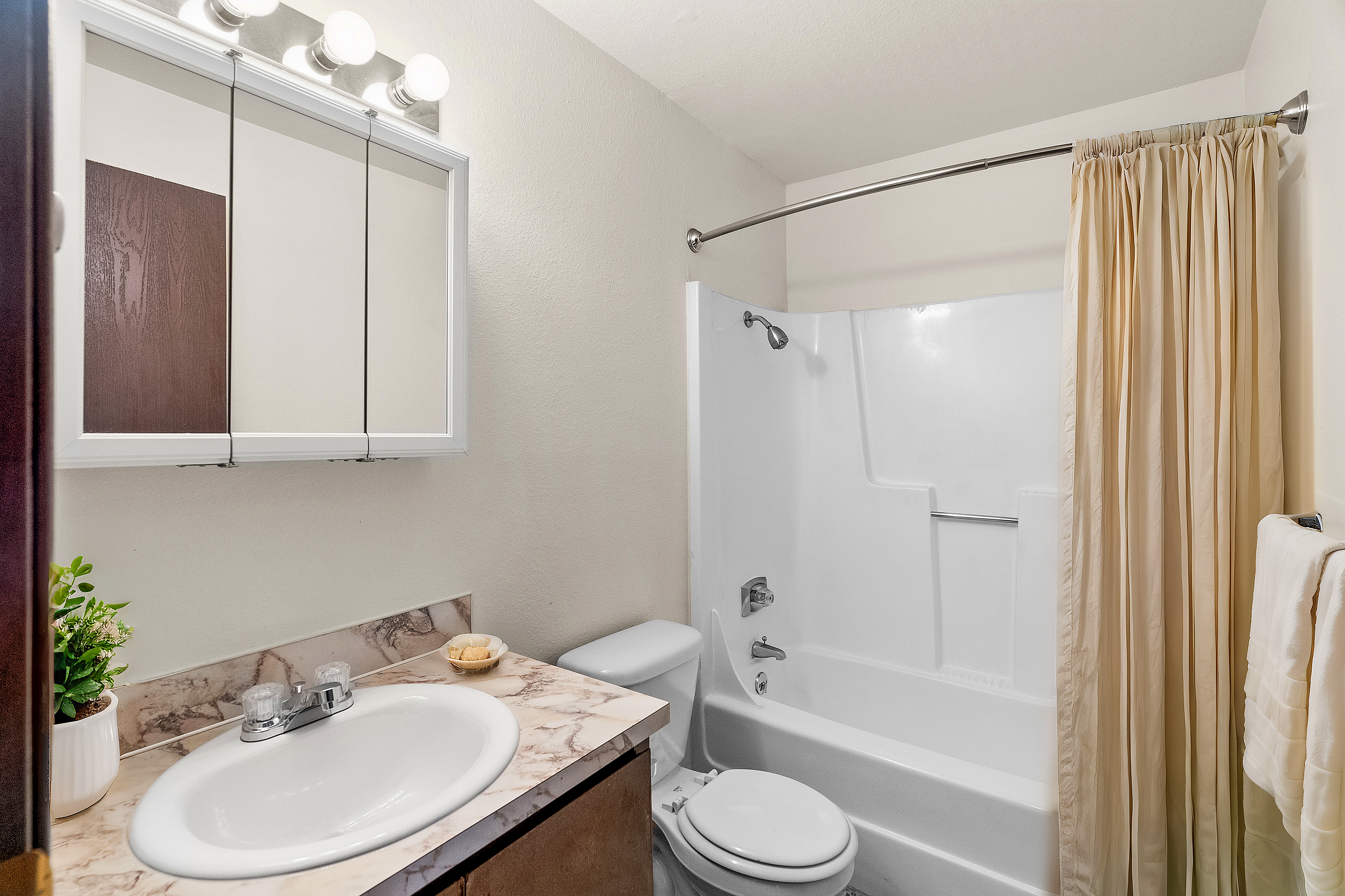 Modern bathroom with elegant marble countertop, mirrored cabinet, and pristine white shower tub ensemble.