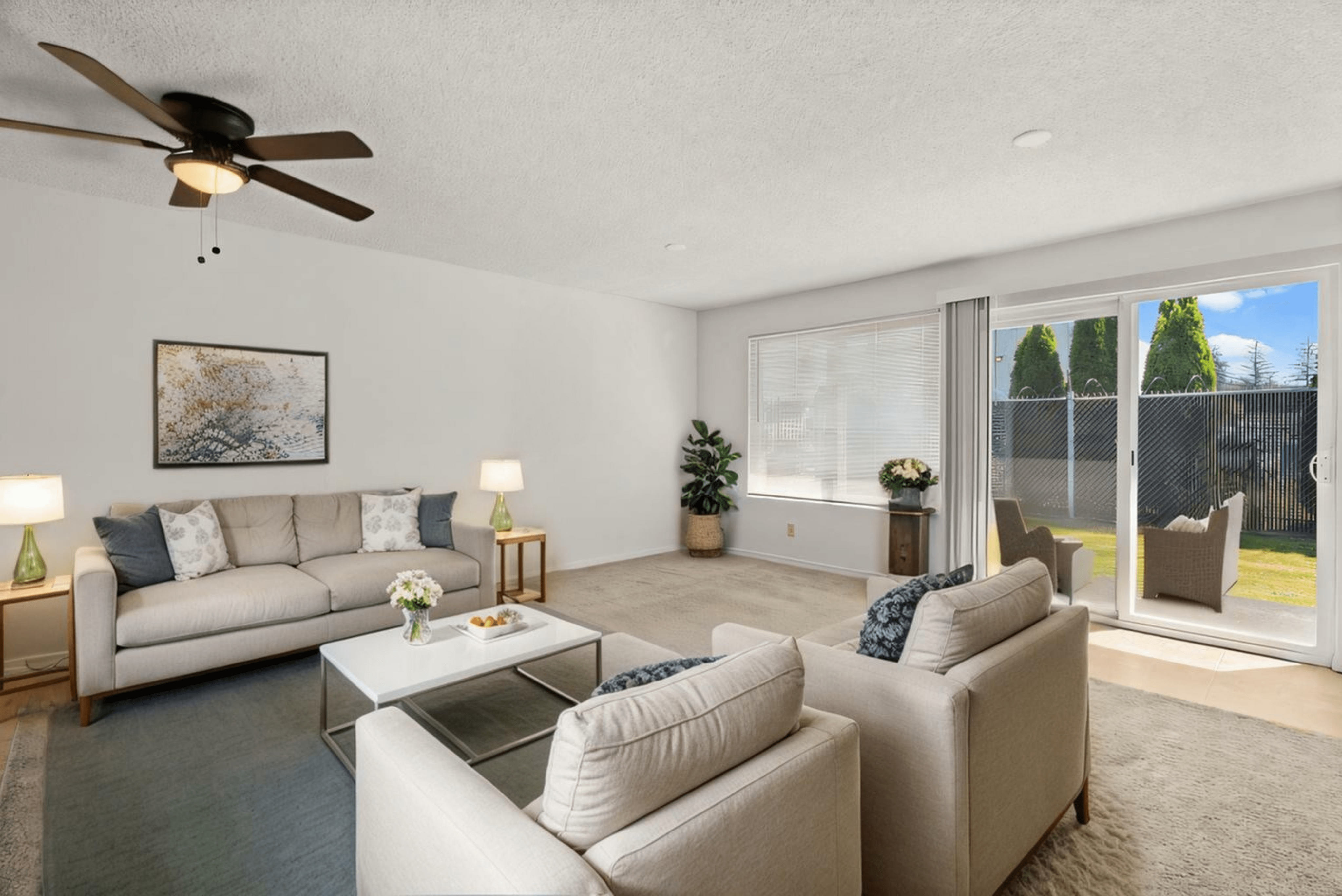 Bright and inviting living room with plush seating, stylish decor, and a large window leading to a private patio.