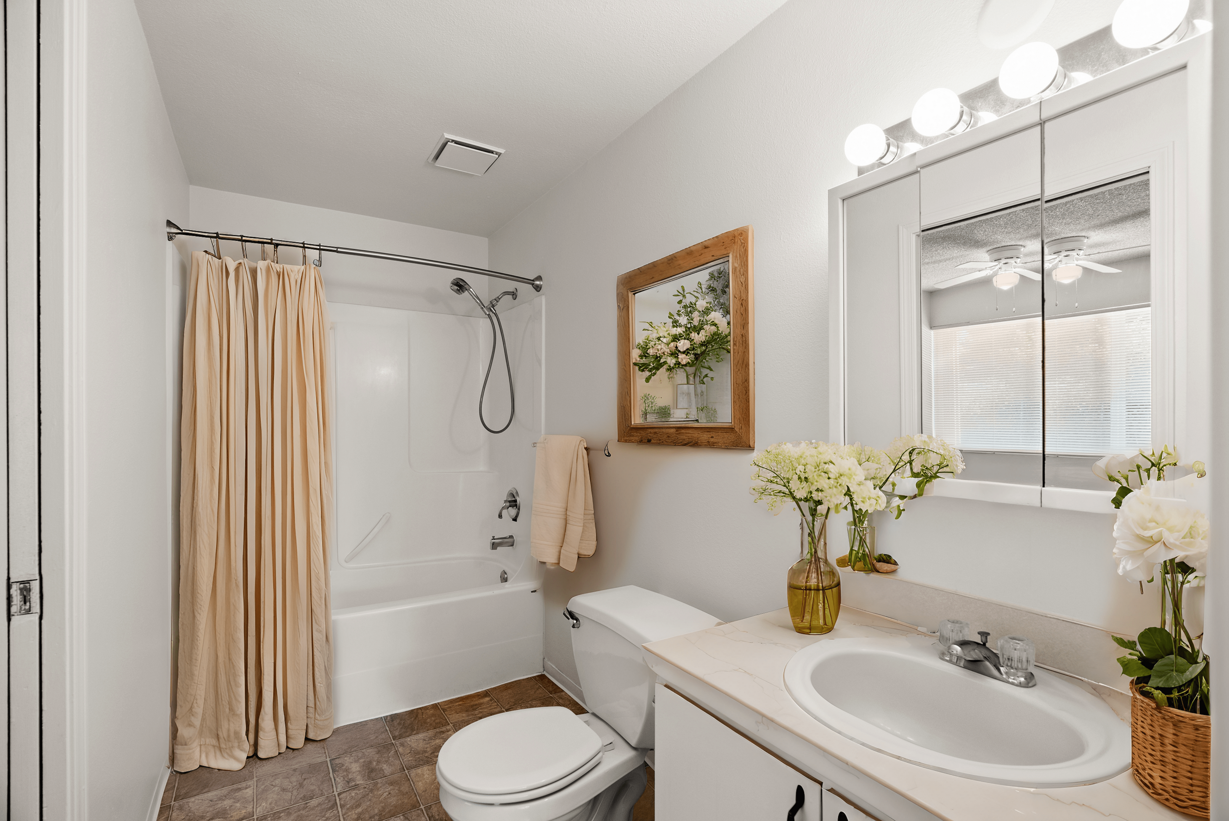 Bright, inviting bathroom with elegant fixtures, decorative flowers, and a clean, modern design.