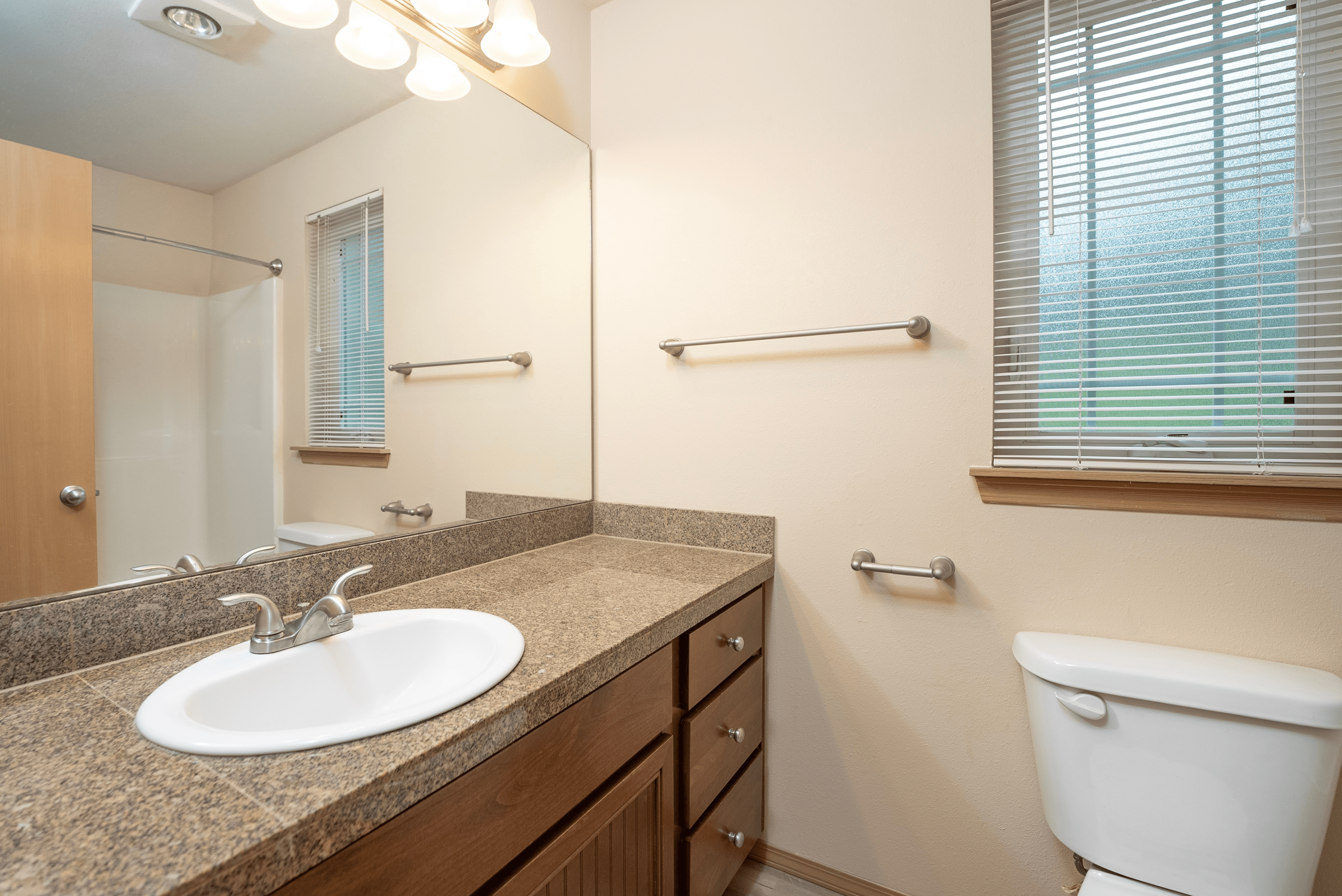 A stylish bathroom featuring dark wood cabinetry, modern countertops, and a sleek design. The space is well-lit, offering a contemporary and elegant feel.
