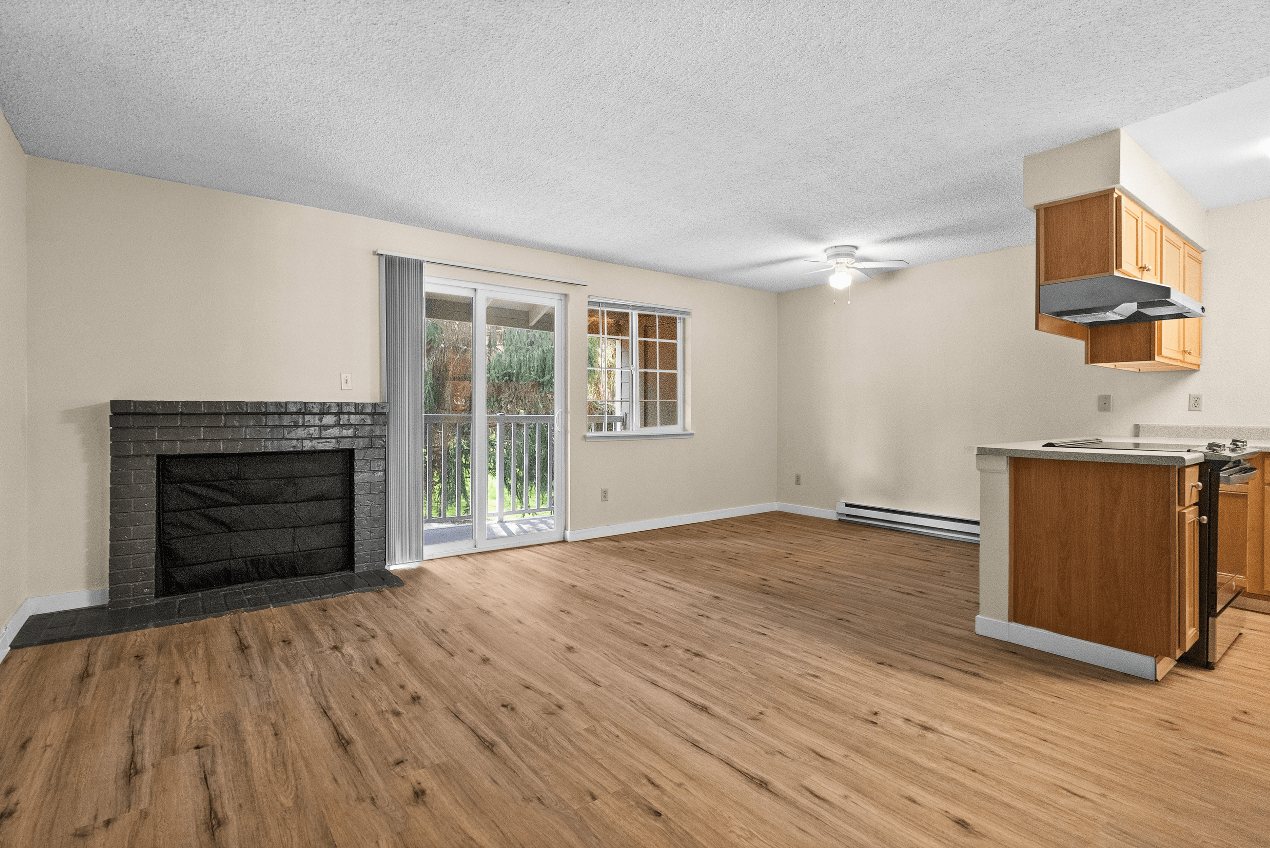 Bright and airy open-concept living space with a modern fireplace, sleek hardwood floors, and access to a private balcony through sliding glass doors.