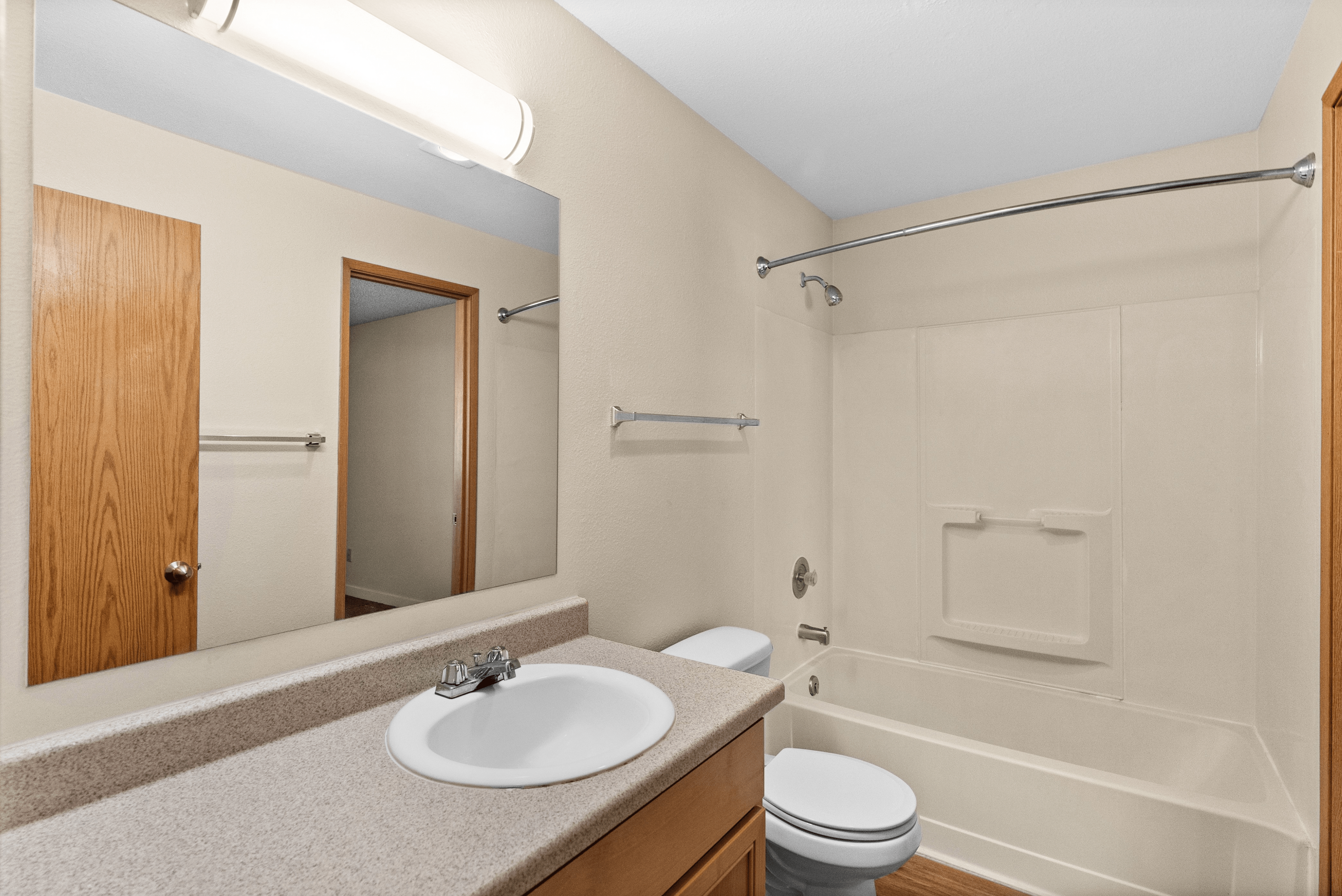 Bright and inviting bathroom with modern fixtures, featuring a sleek vanity, spacious mirror, and elegant bathtub.