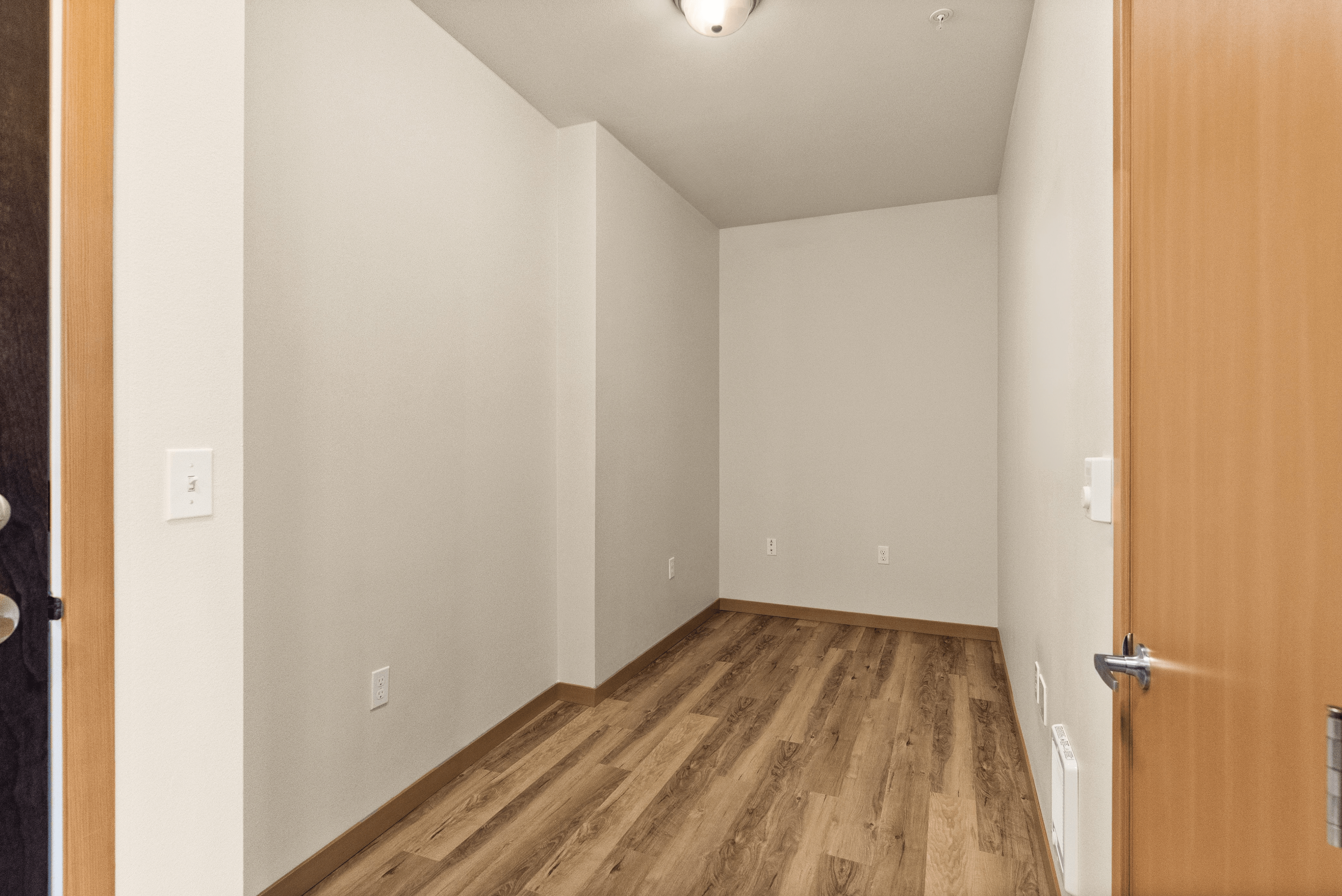 Inviting den with elegant wood flooring and soft neutral walls, perfect for a cozy office or guest space.