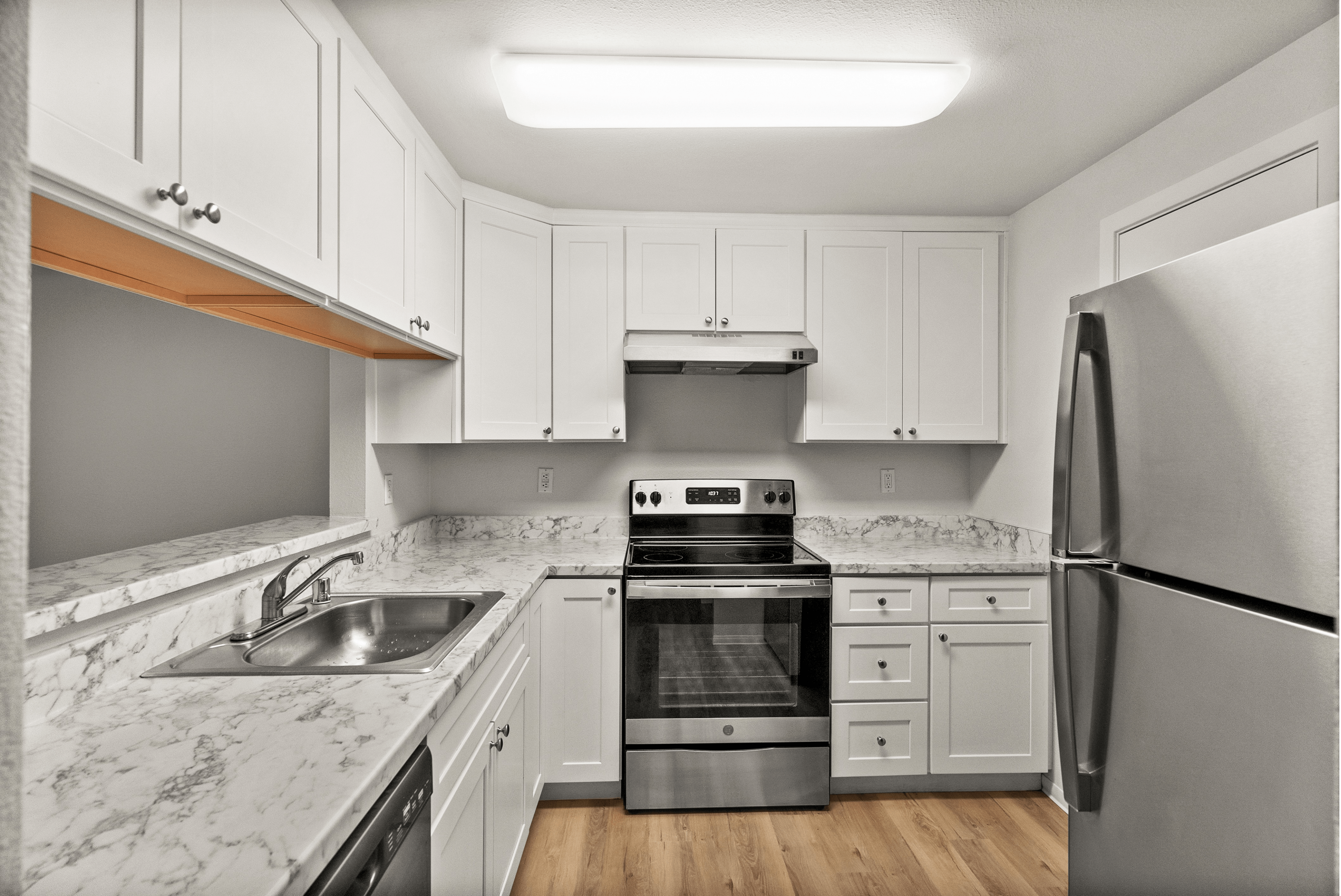Modern kitchen with sleek stainless steel appliances, elegant white cabinetry, and chic marble countertops.